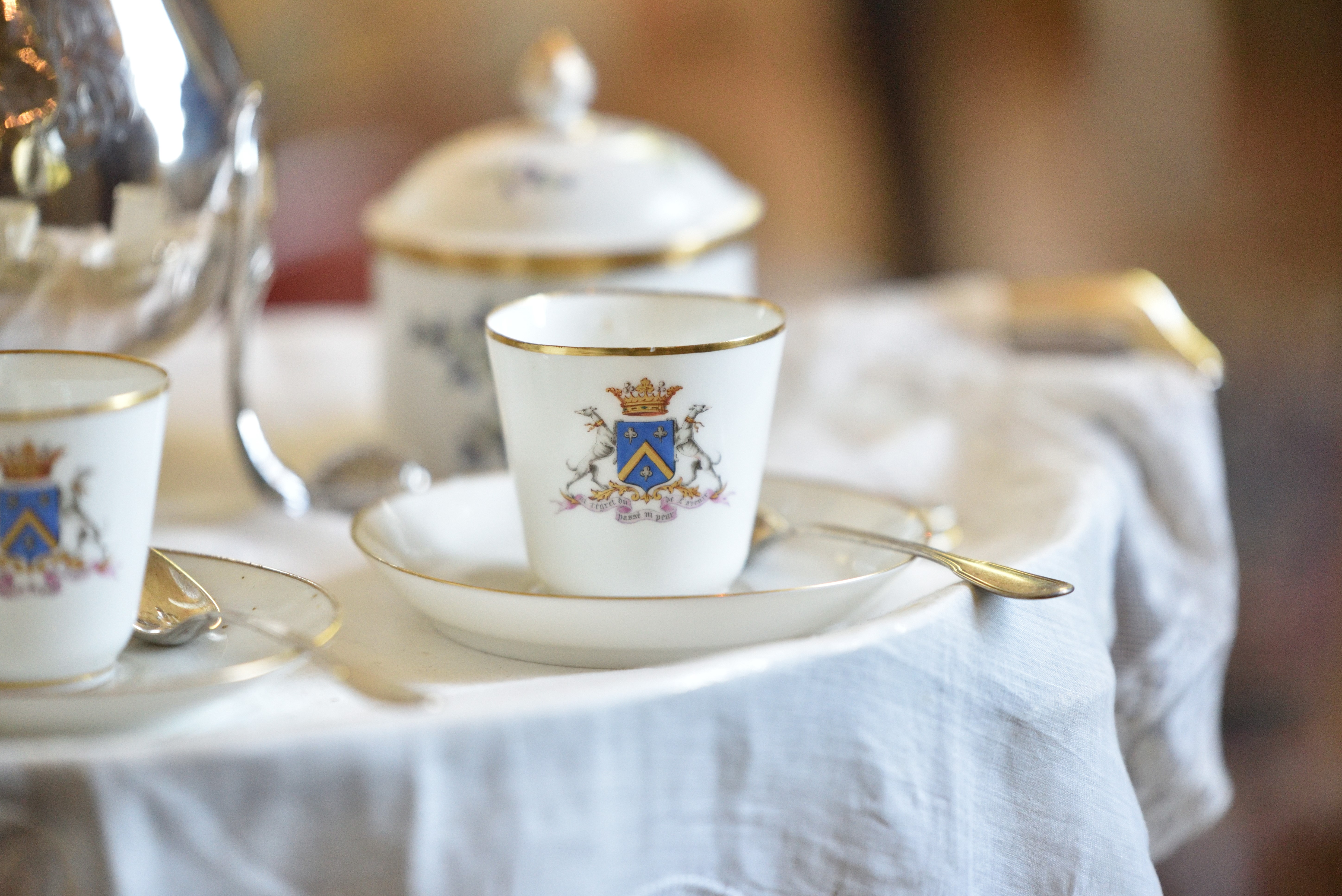 Teacup with crest and spoon on a table HD Wallpaper