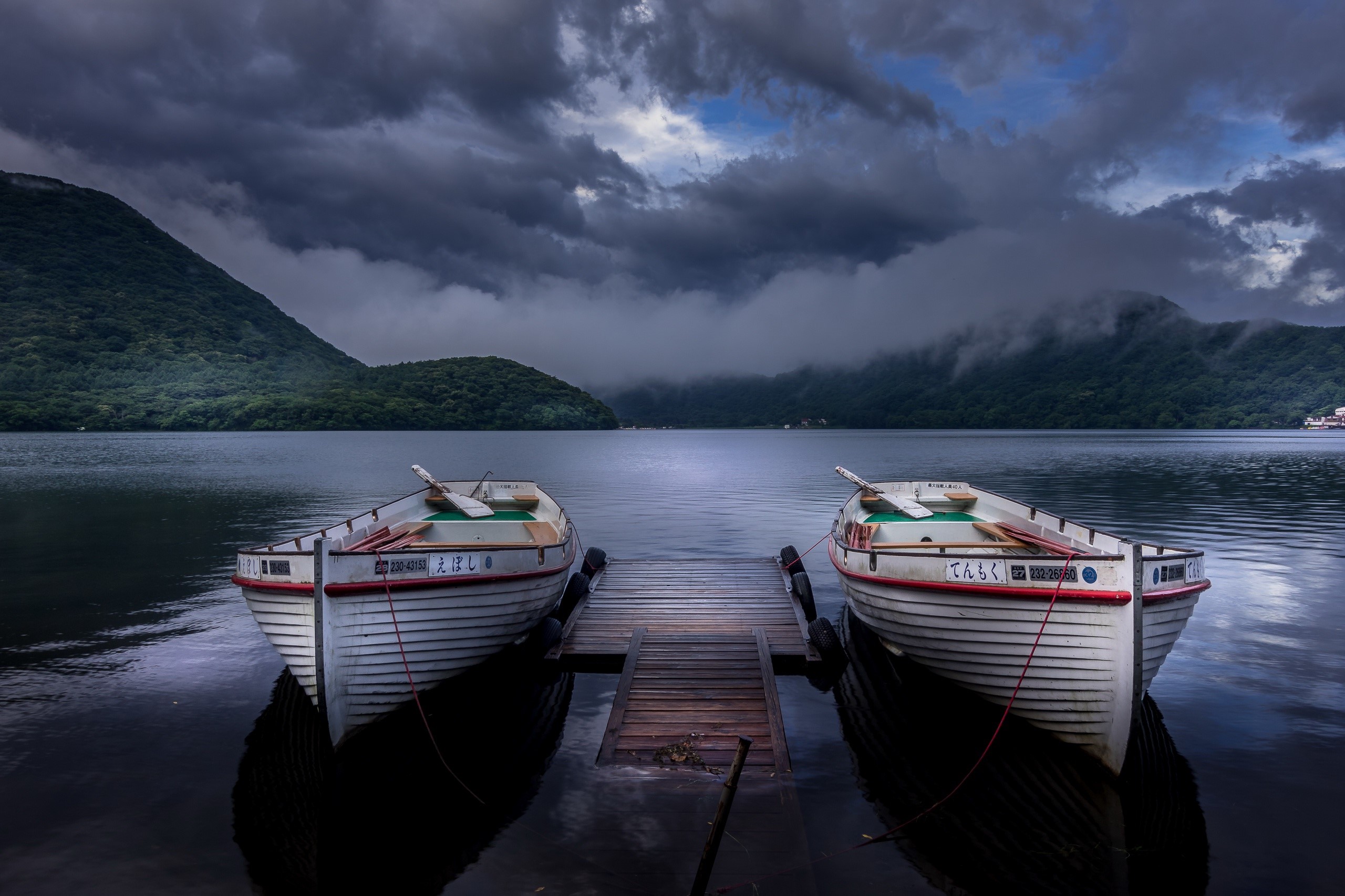 Two boats docked on a lake in Japan under stormy clouds HD Wallpaper