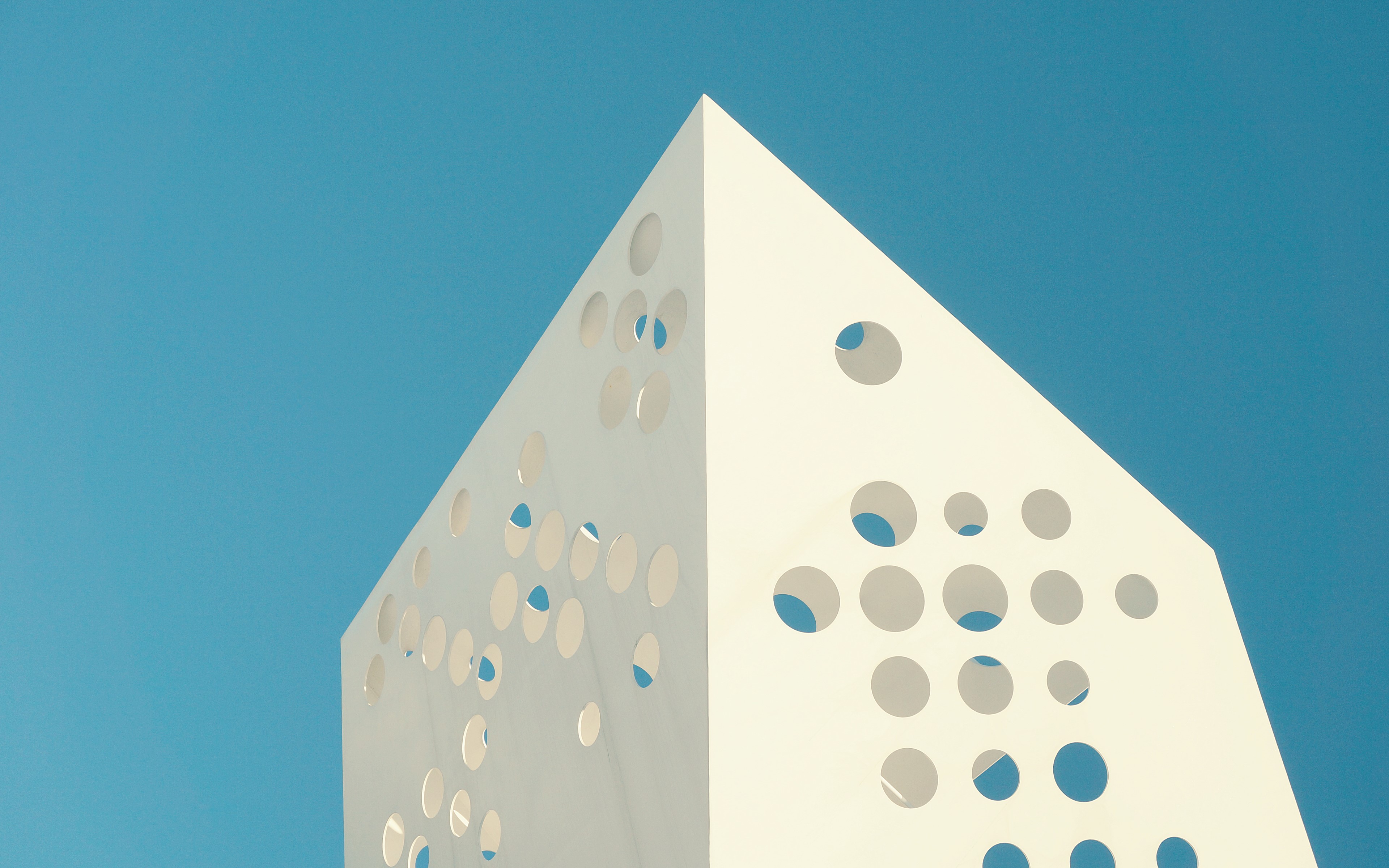 Abstract white structure with circular cutouts against blue sky HD Wallpaper