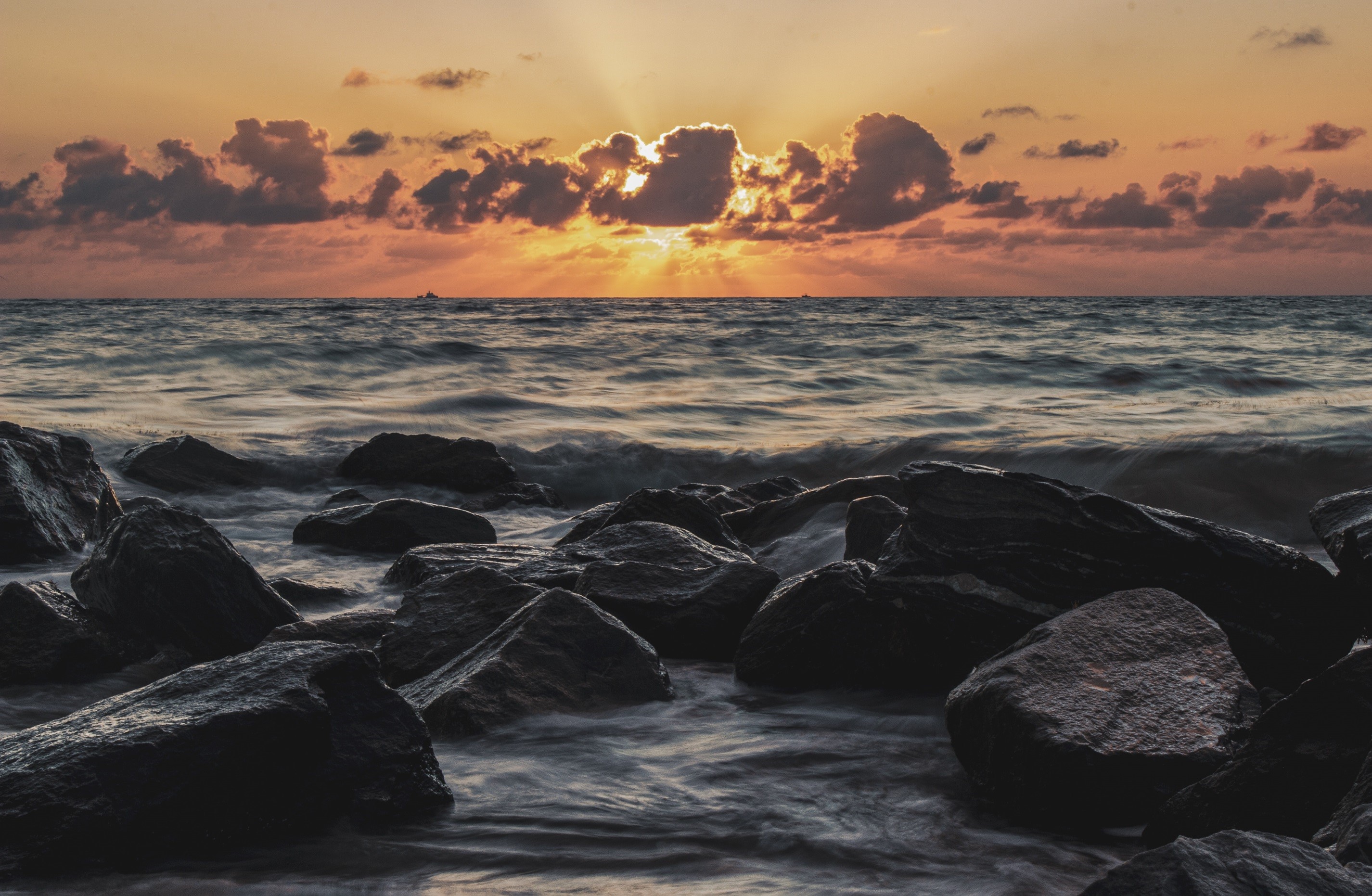Sunset over the ocean with rocks in the foreground HD Wallpaper