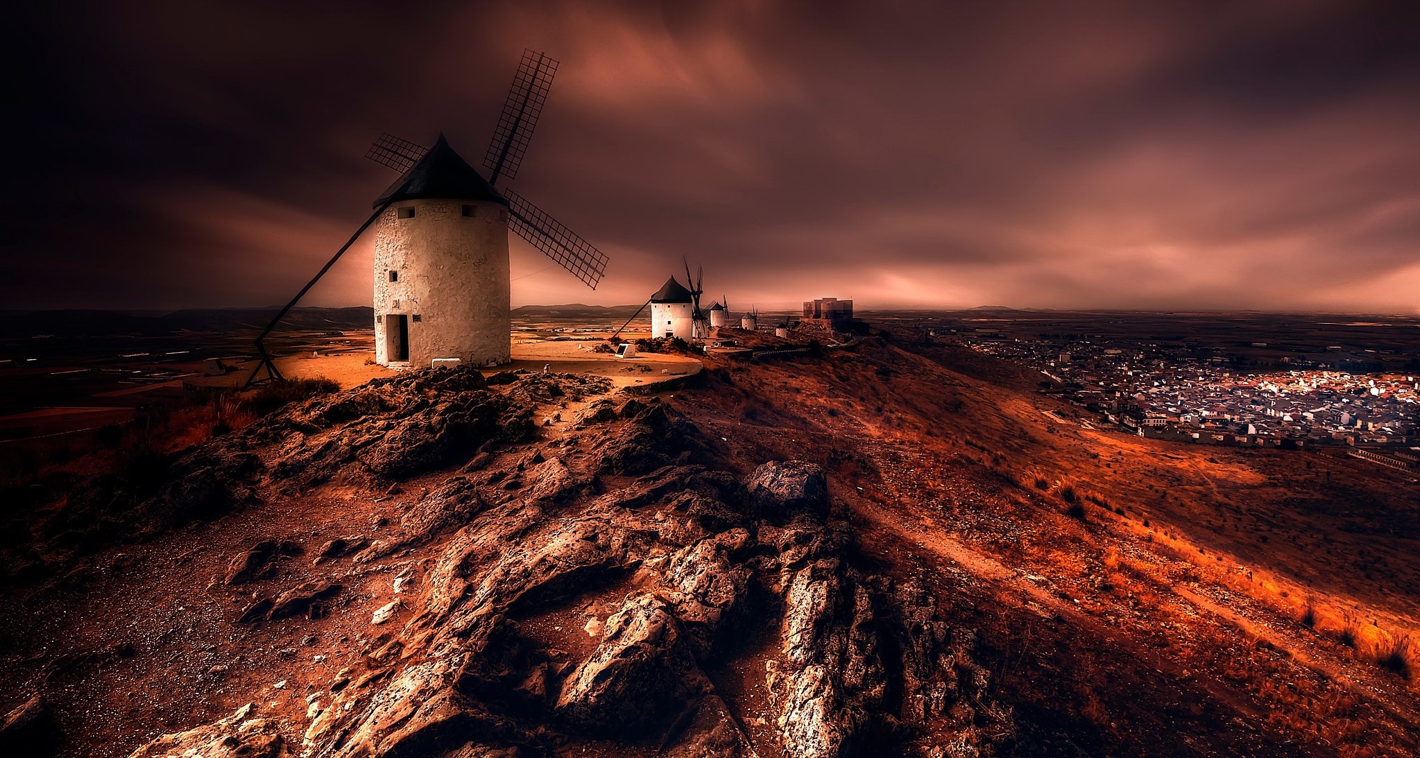 Windmills on a hill overlooking a town at sunset HD Wallpaper