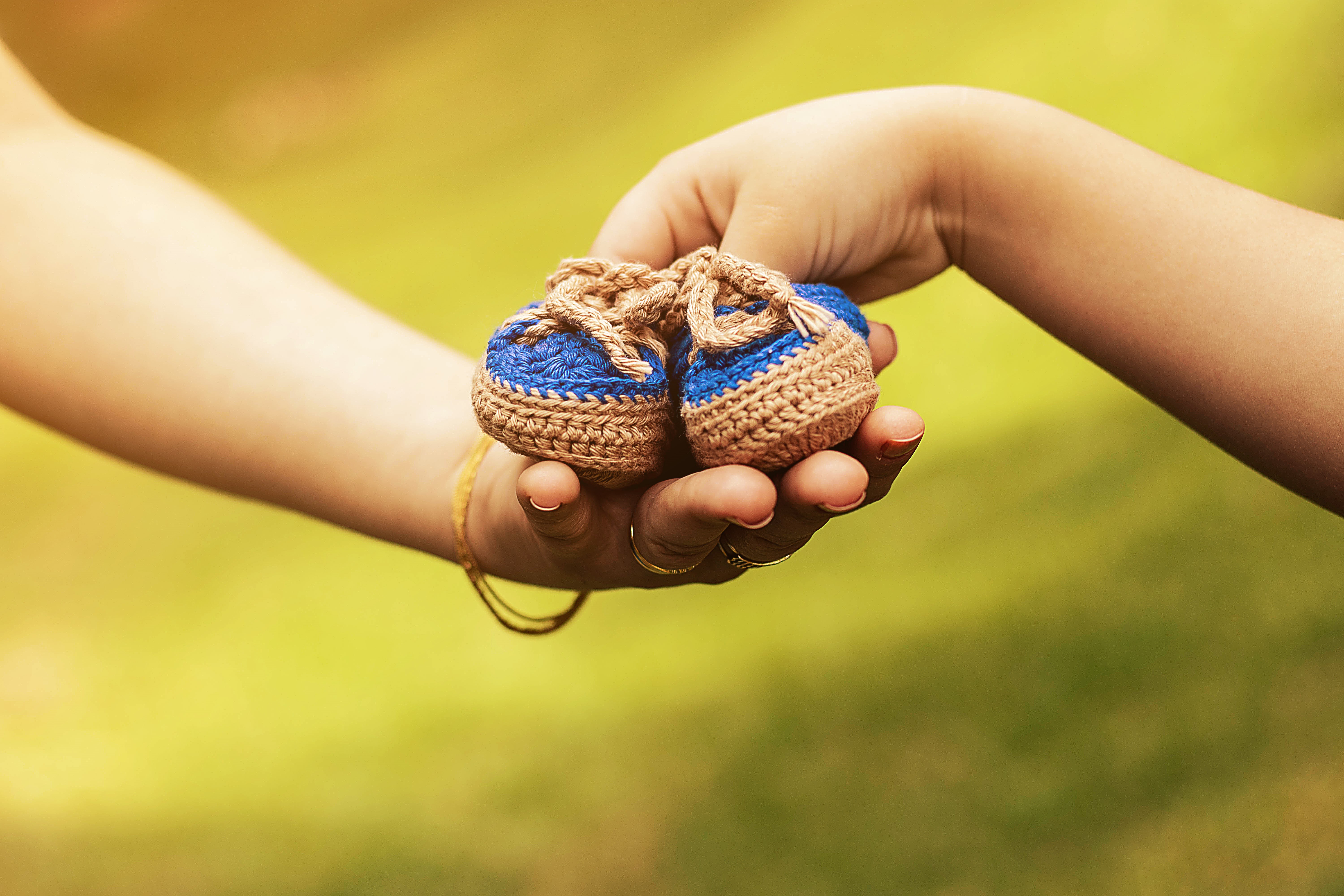 Hands holding baby booties HD Wallpaper