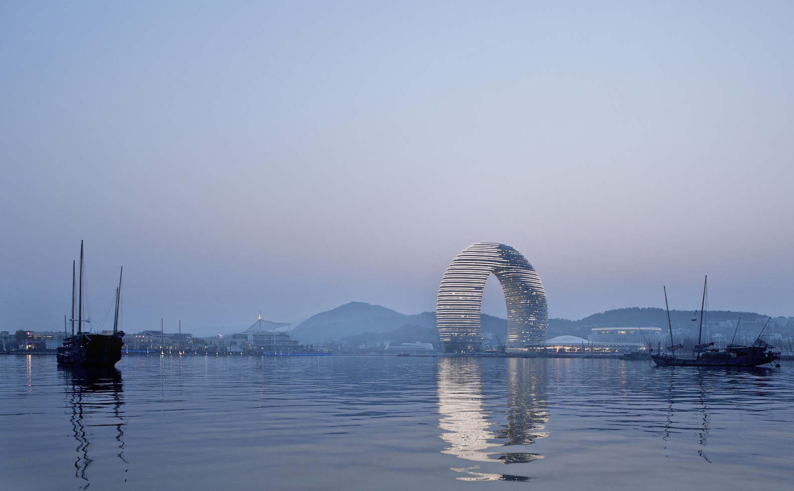 Modern circular building on a waterfront with boats HD Wallpaper
