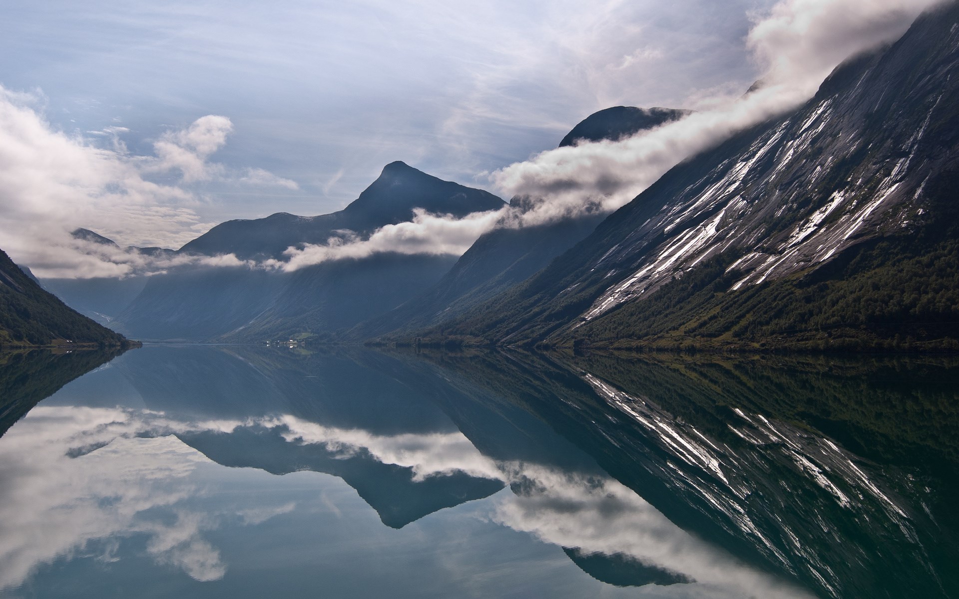 Mountains reflected in a calm lake under a cloudy sky HD Wallpaper