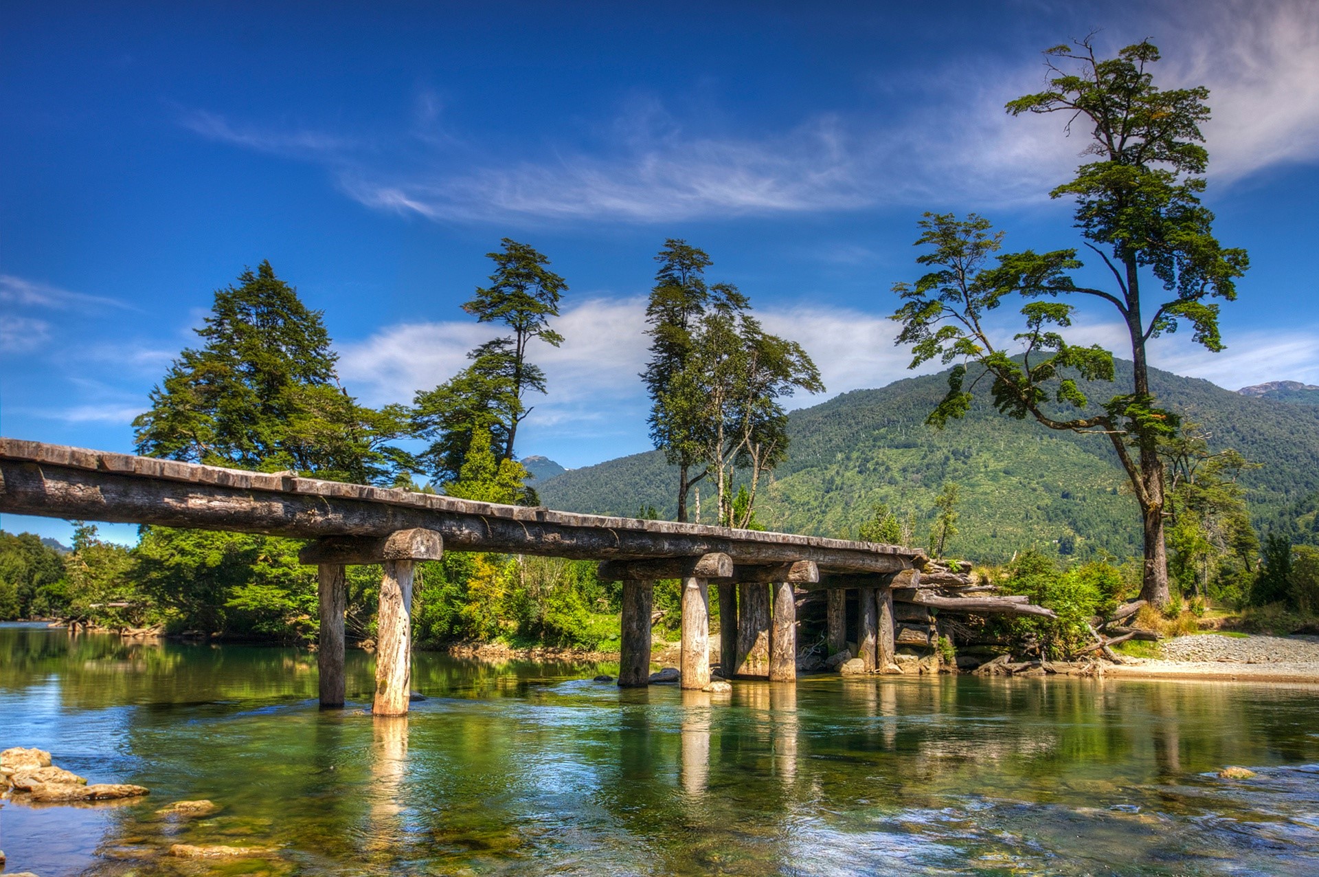 Wooden bridge over a river in Chile with trees and mountains HD Wallpaper