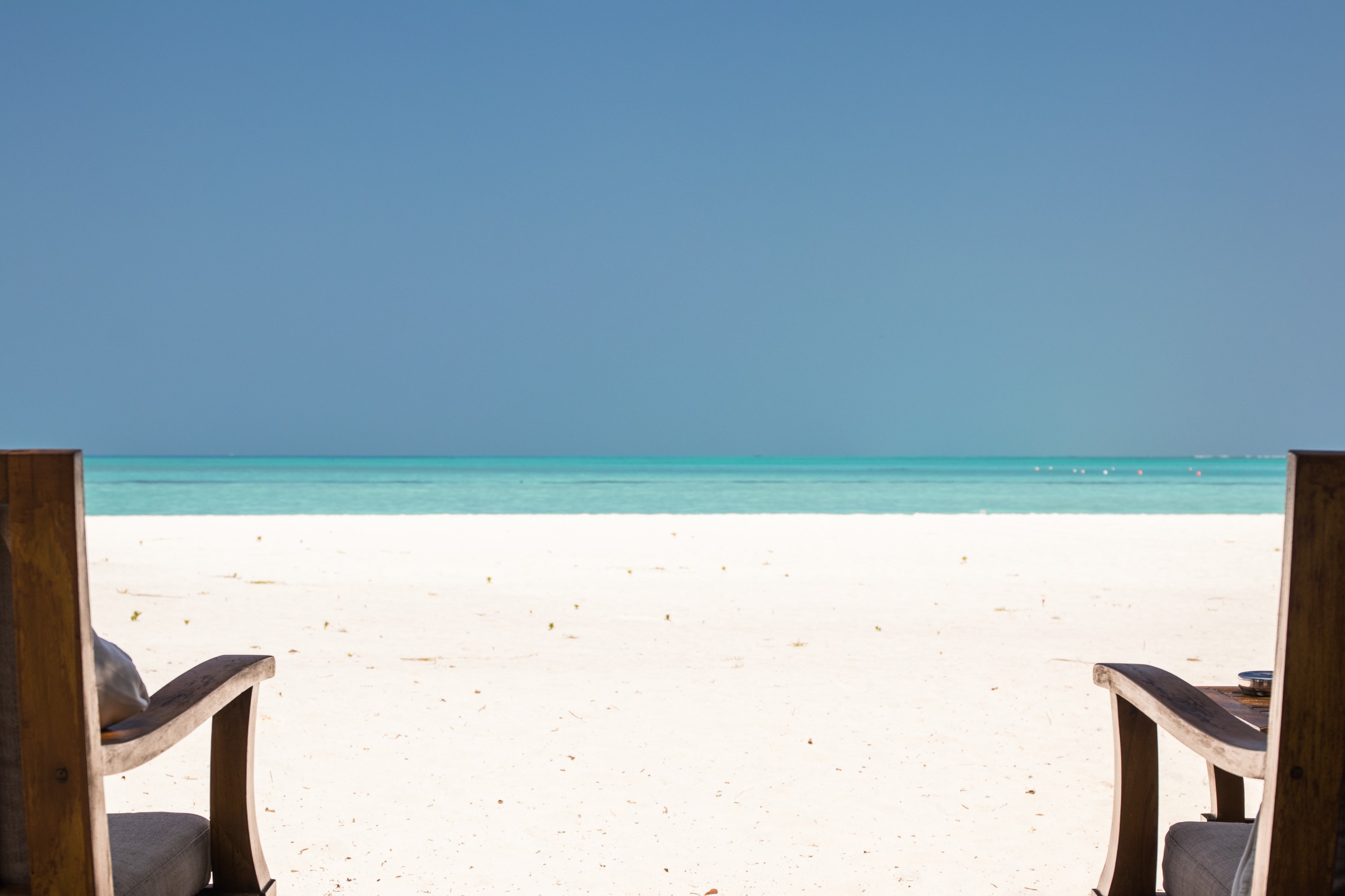 Two chairs on a tropical beach overlooking the ocean HD Wallpaper