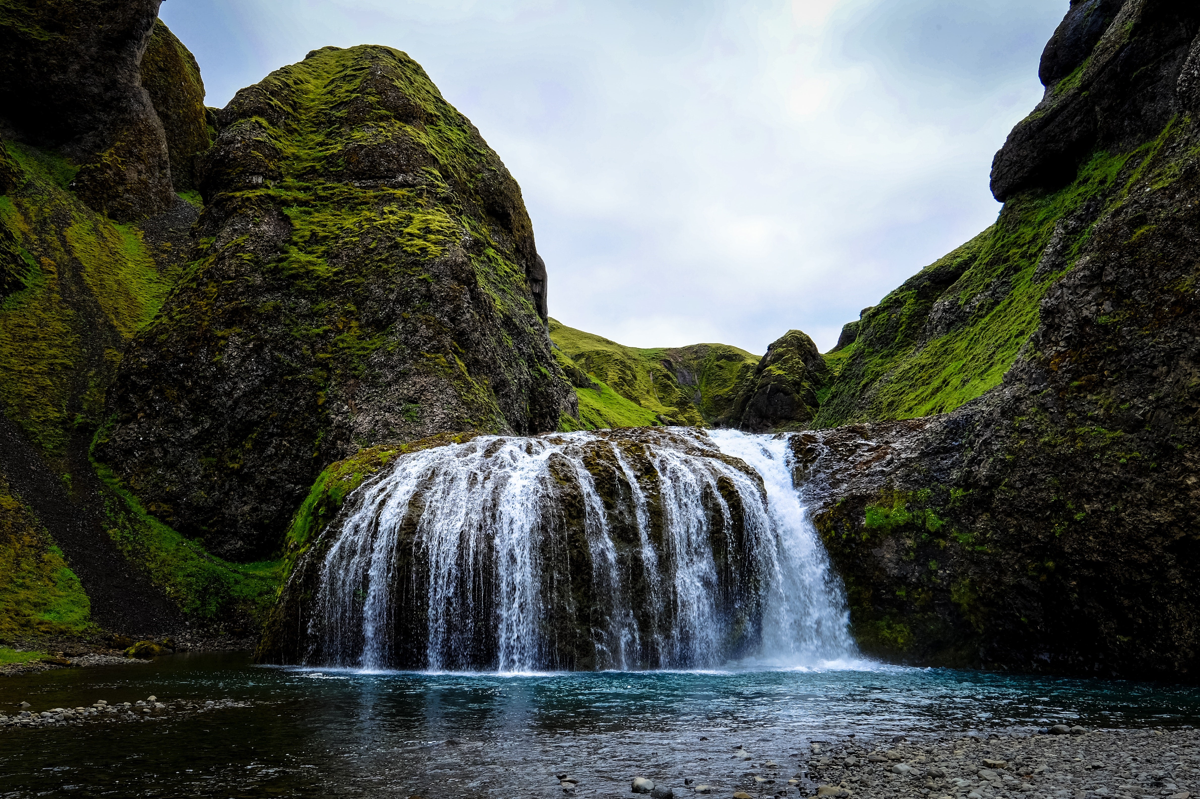 Mossy cliffs surround a wide waterfall into a pool HD Wallpaper