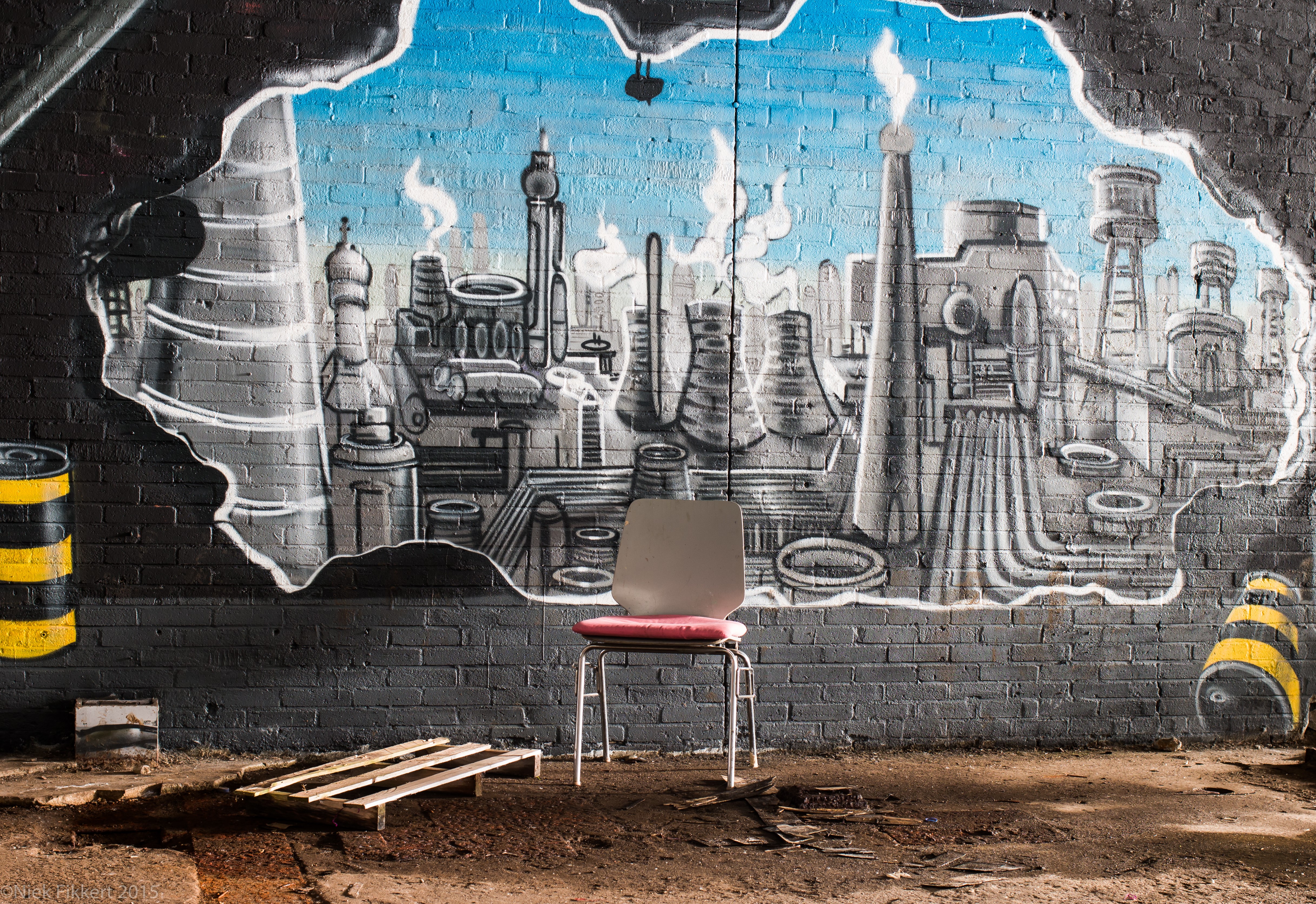 Graffiti of a factory on a brick wall with a chair HD Wallpaper