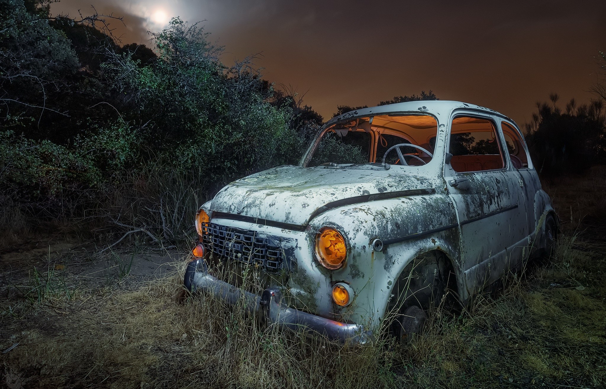 Abandoned vintage car in overgrown weeds at night HD Wallpaper