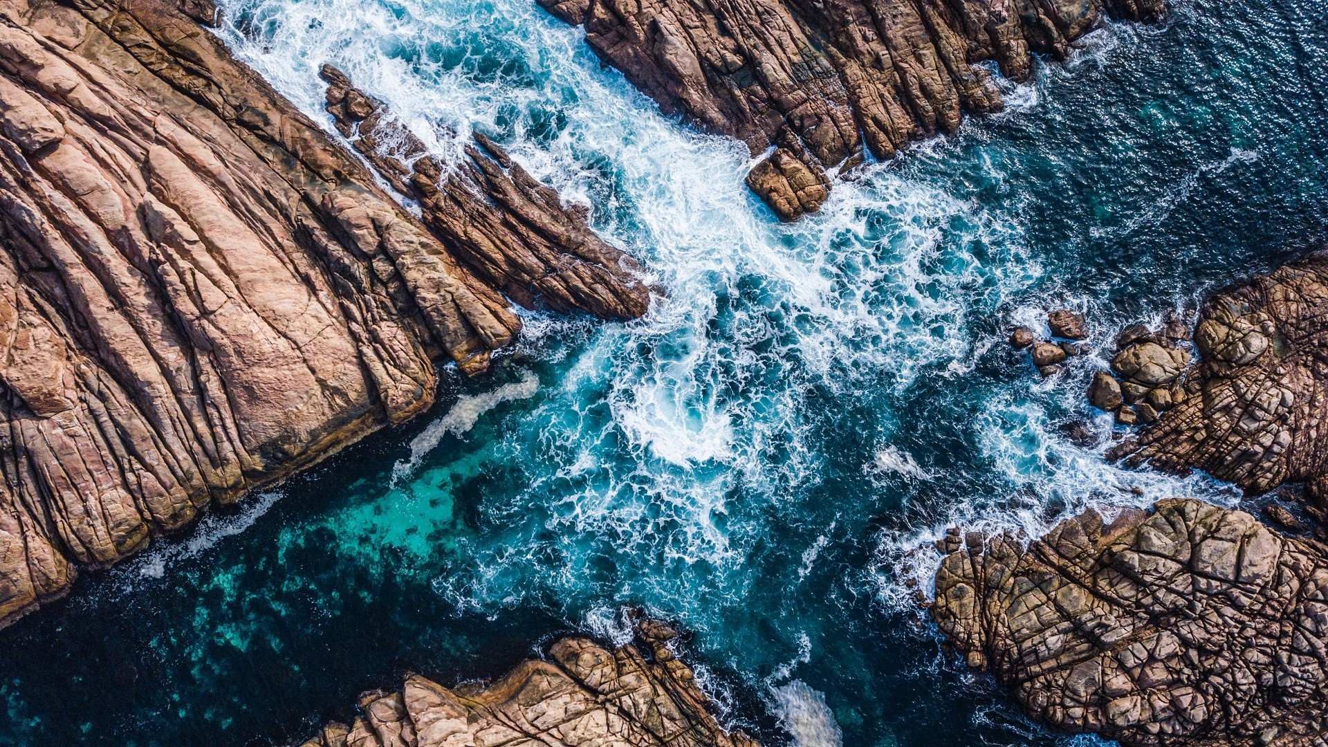 Aerial view of ocean waves crashing on rocky coastline HD Wallpaper