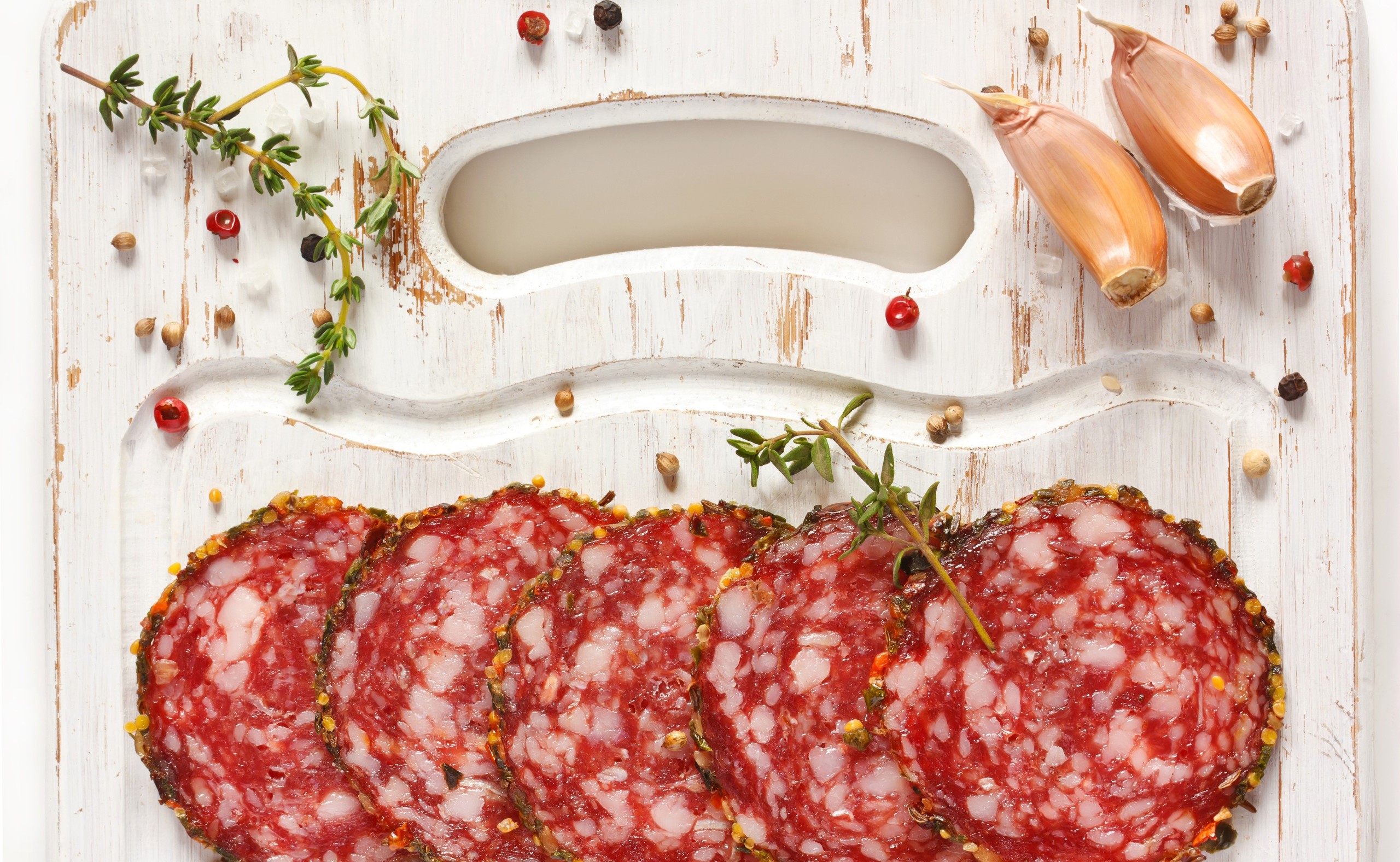Sliced salami with garlic and herbs on a cutting board HD Wallpaper