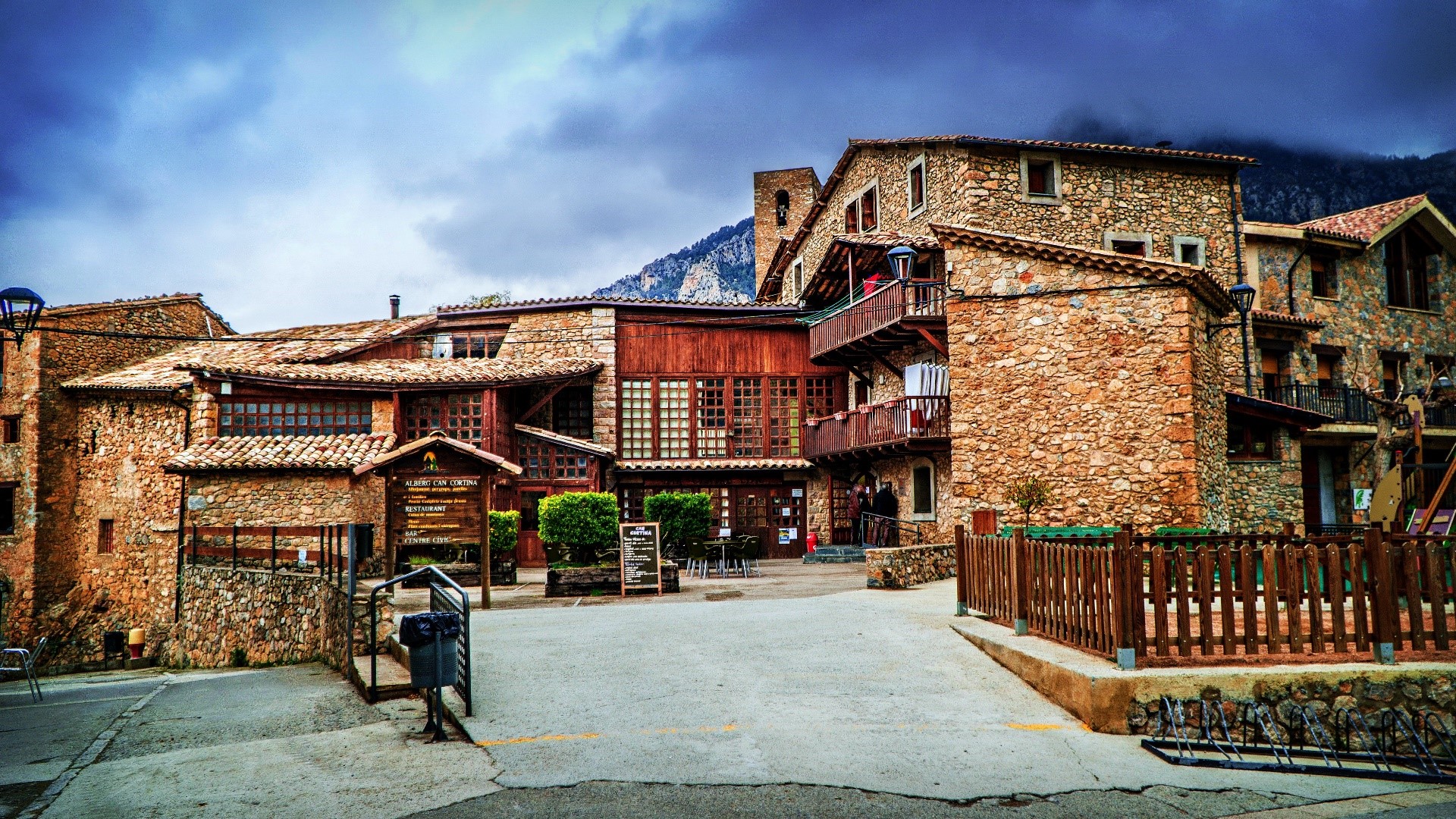 Stone buildings in a mountain town under a cloudy sky HD Wallpaper