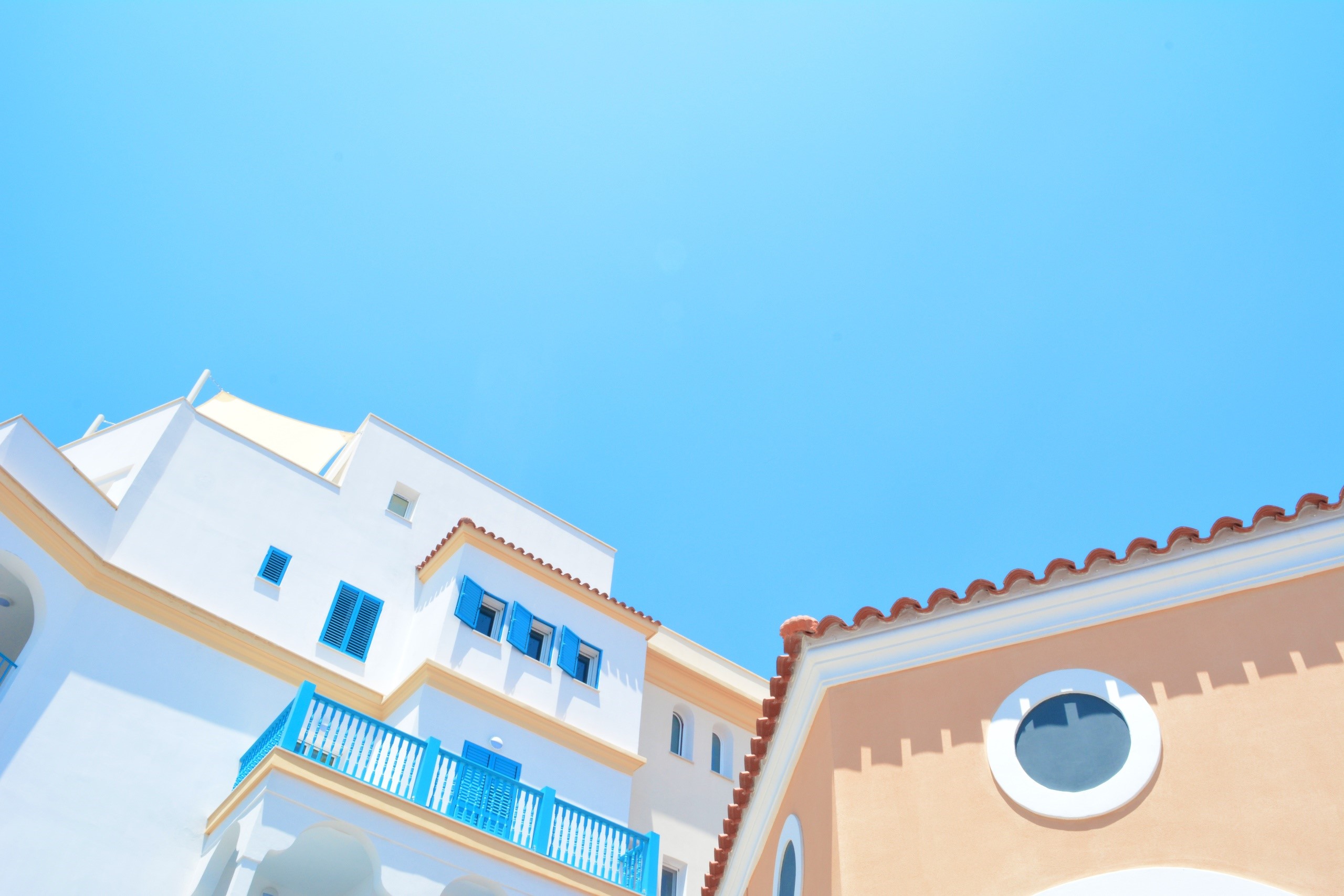 White and peach buildings under a clear blue sky HD Wallpaper
