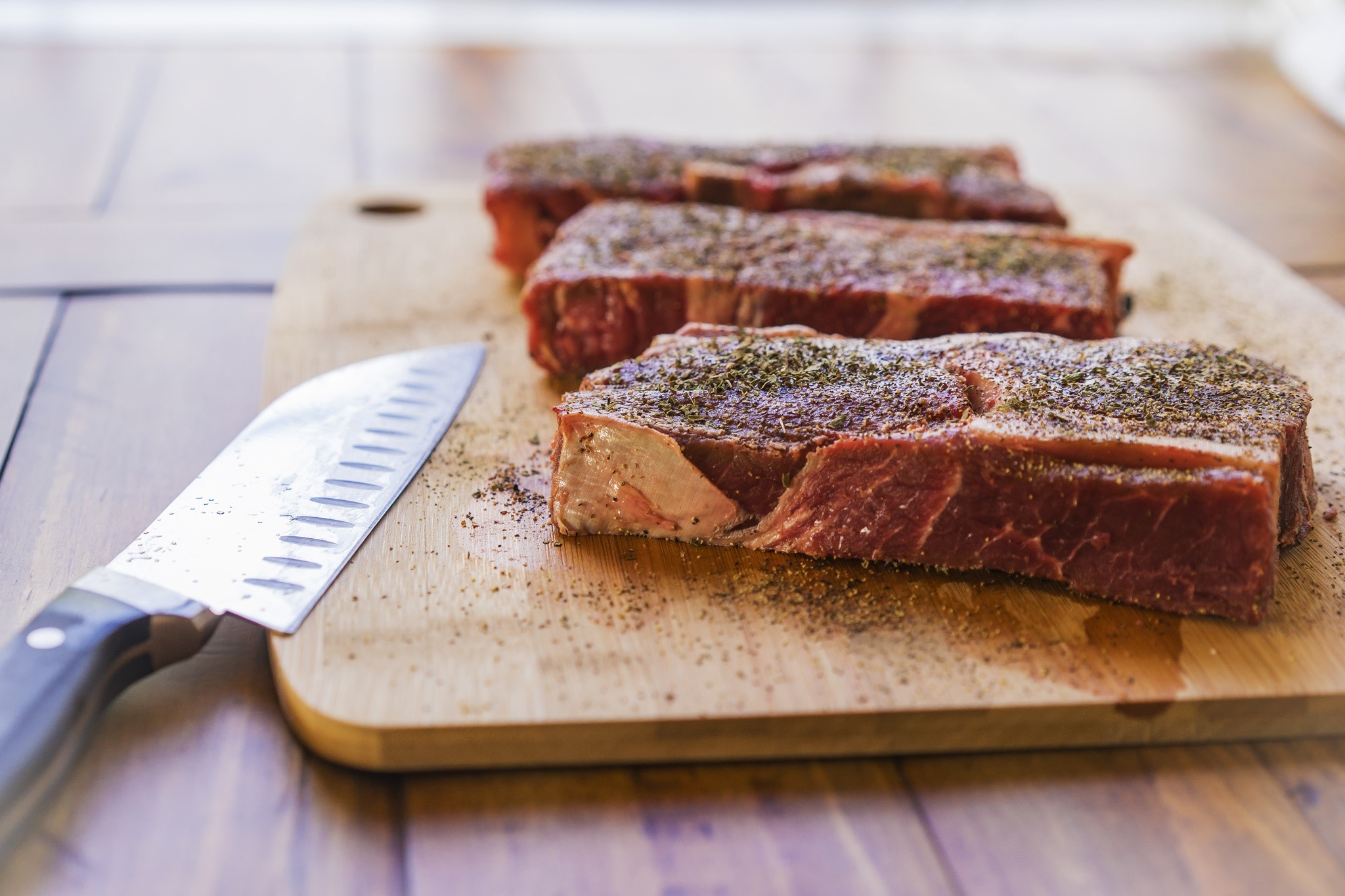 Raw steaks seasoned on a cutting board with a knife HD Wallpaper