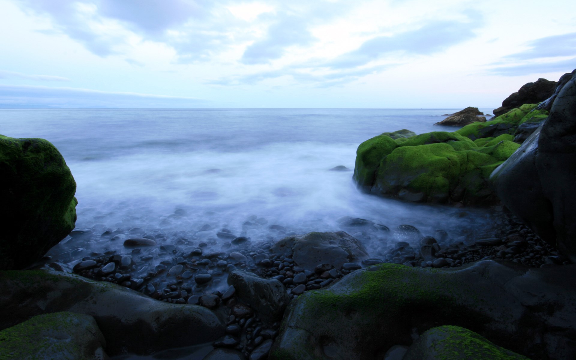 Mossy rocks on a rocky shore with ocean waves HD Wallpaper