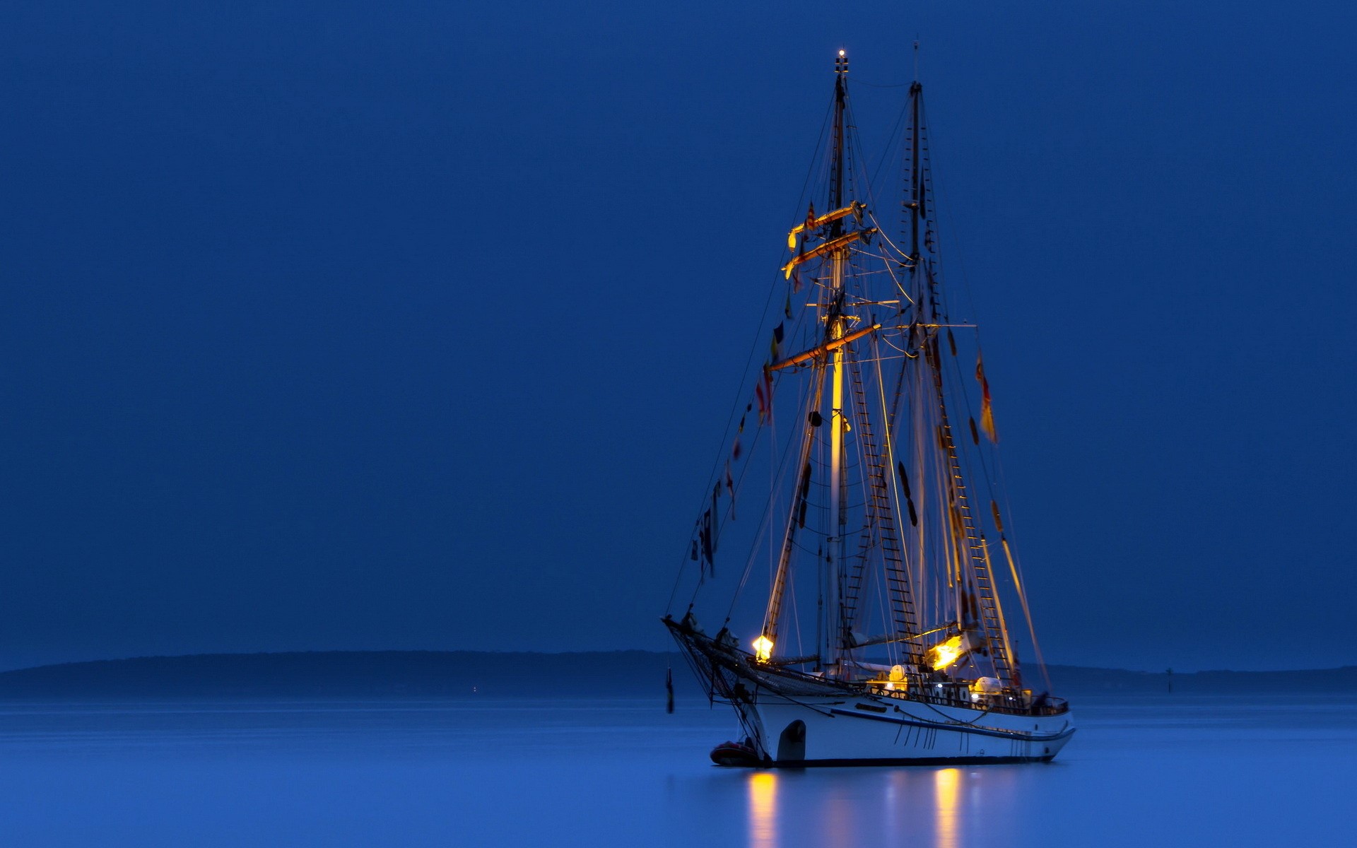 Sailing ship illuminated at night on calm water HD Wallpaper