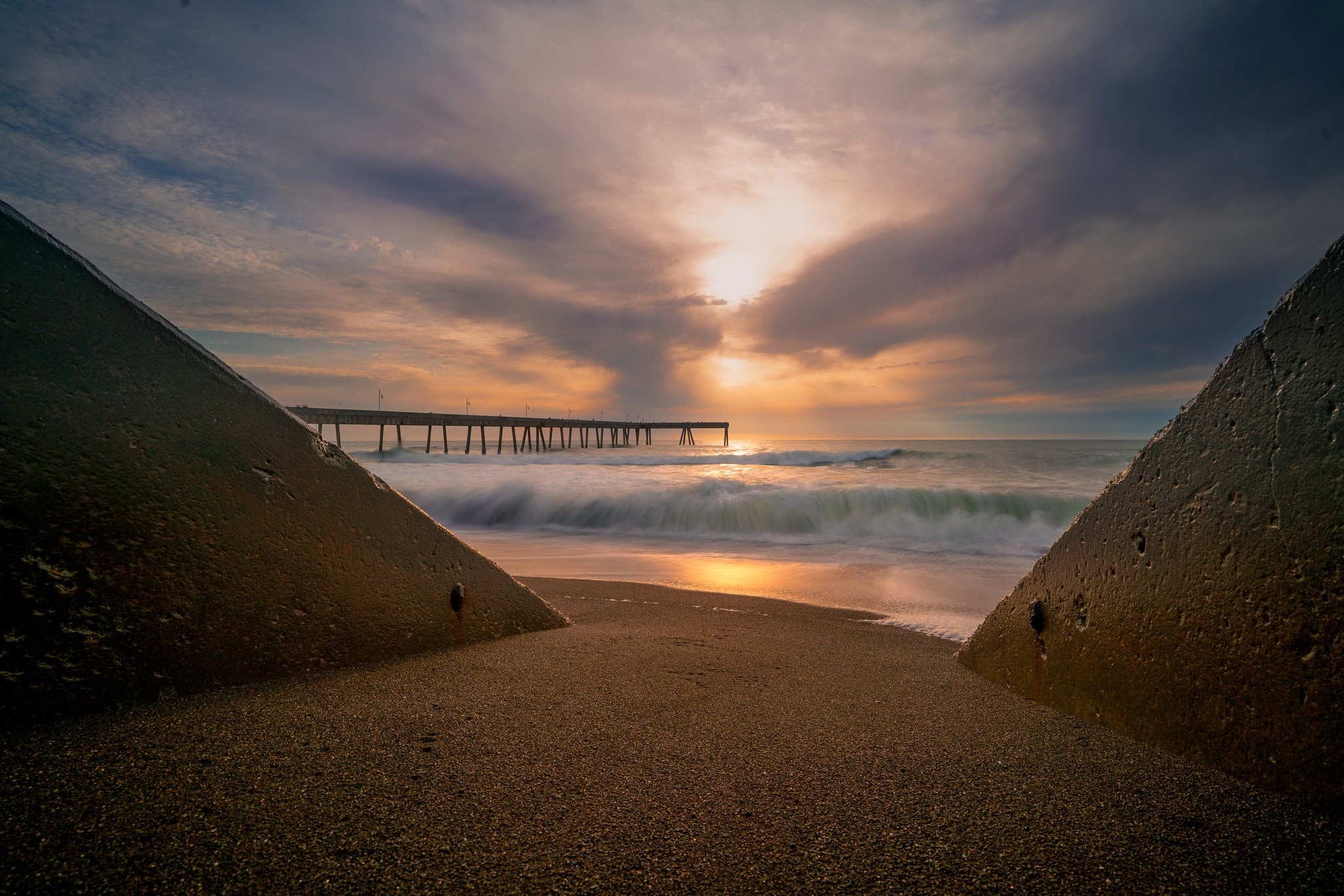 Beach pier at sunset with crashing waves HD Wallpaper