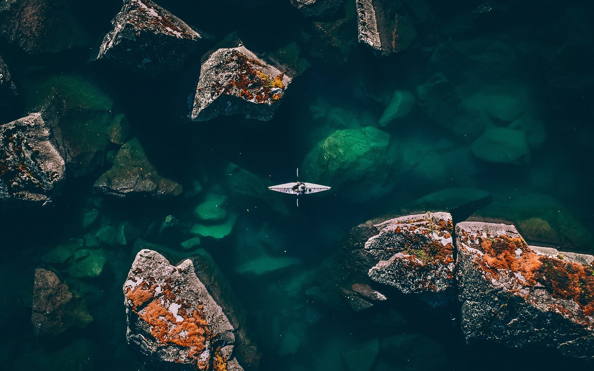 Kayaker in a rocky cove from above HD Wallpaper