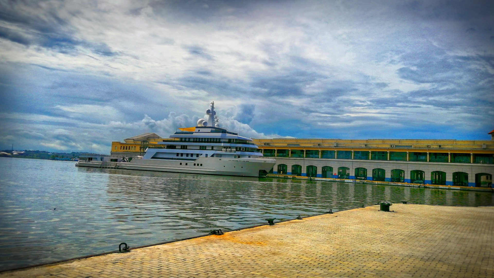 Large yacht docked at a pier with a building in the background HD Wallpaper