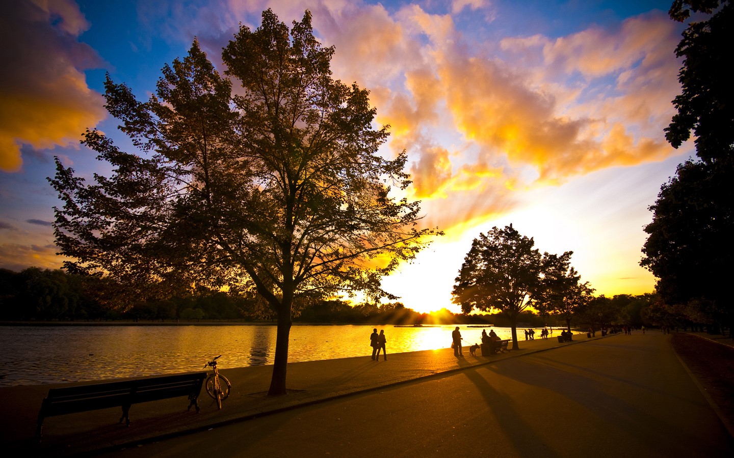 Sunset over a lake with people walking HD Wallpaper