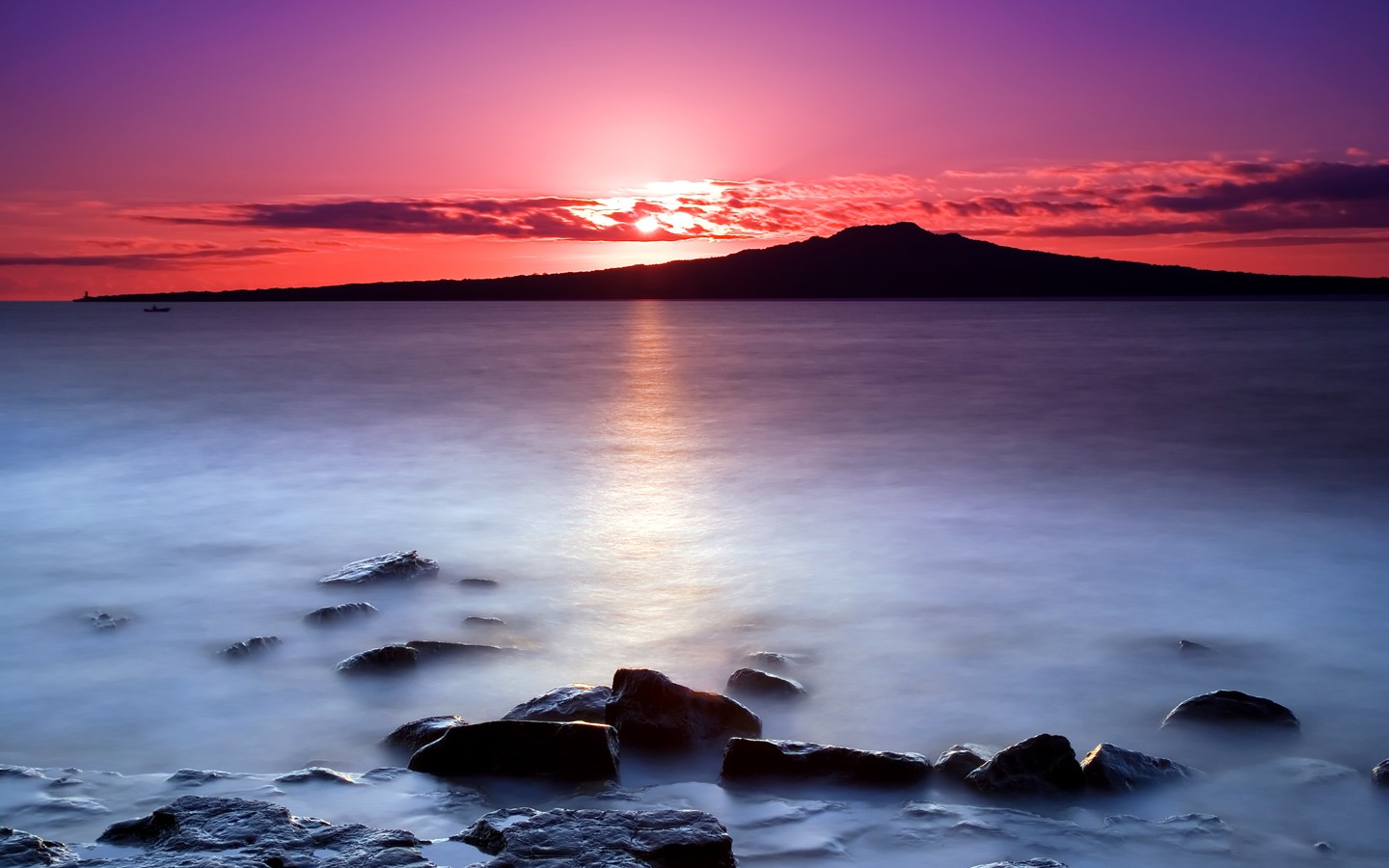 Sunset over water with island silhouette and rocks HD Wallpaper