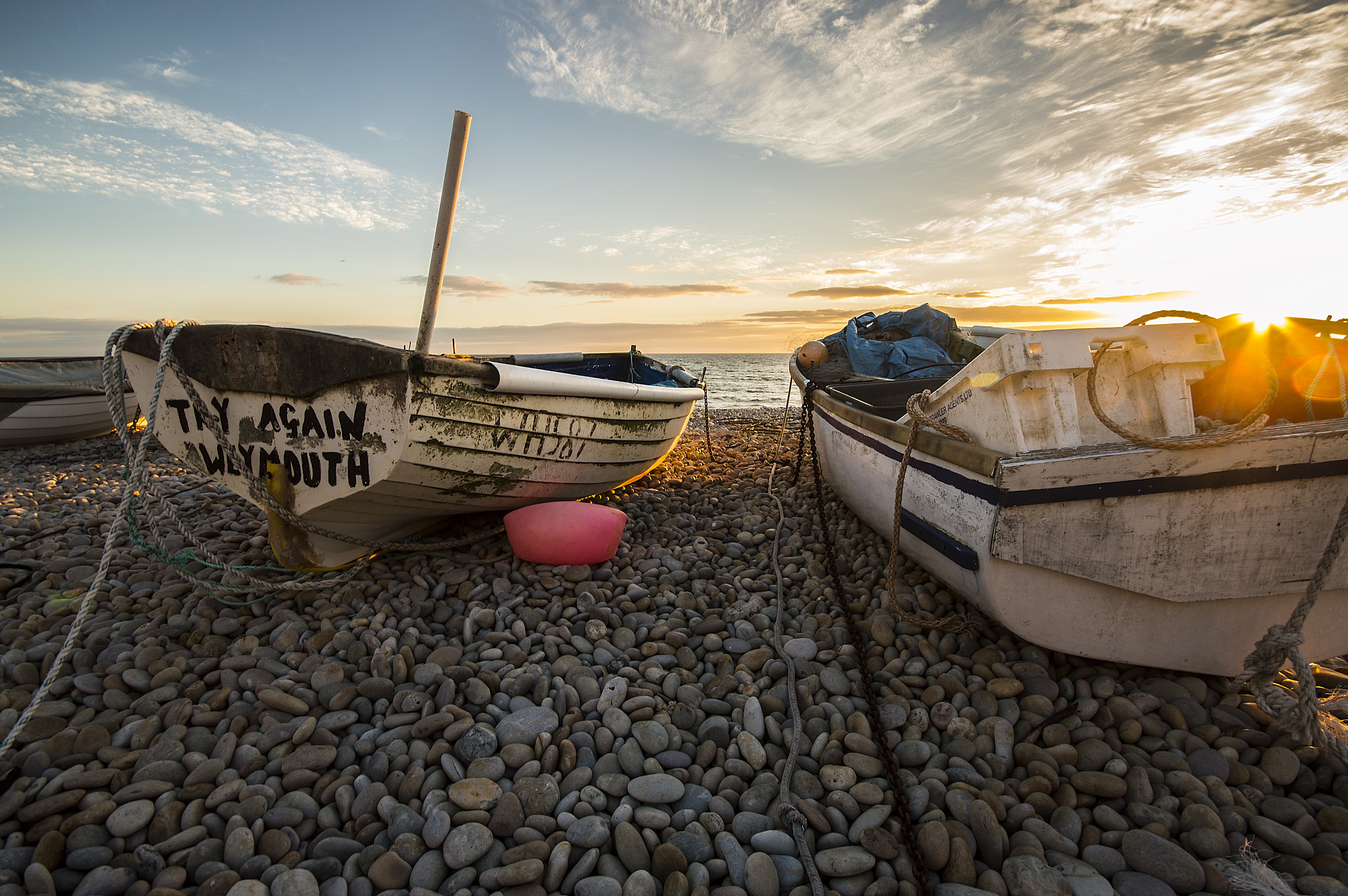 Boats on a rocky beach at sunset HD Wallpaper