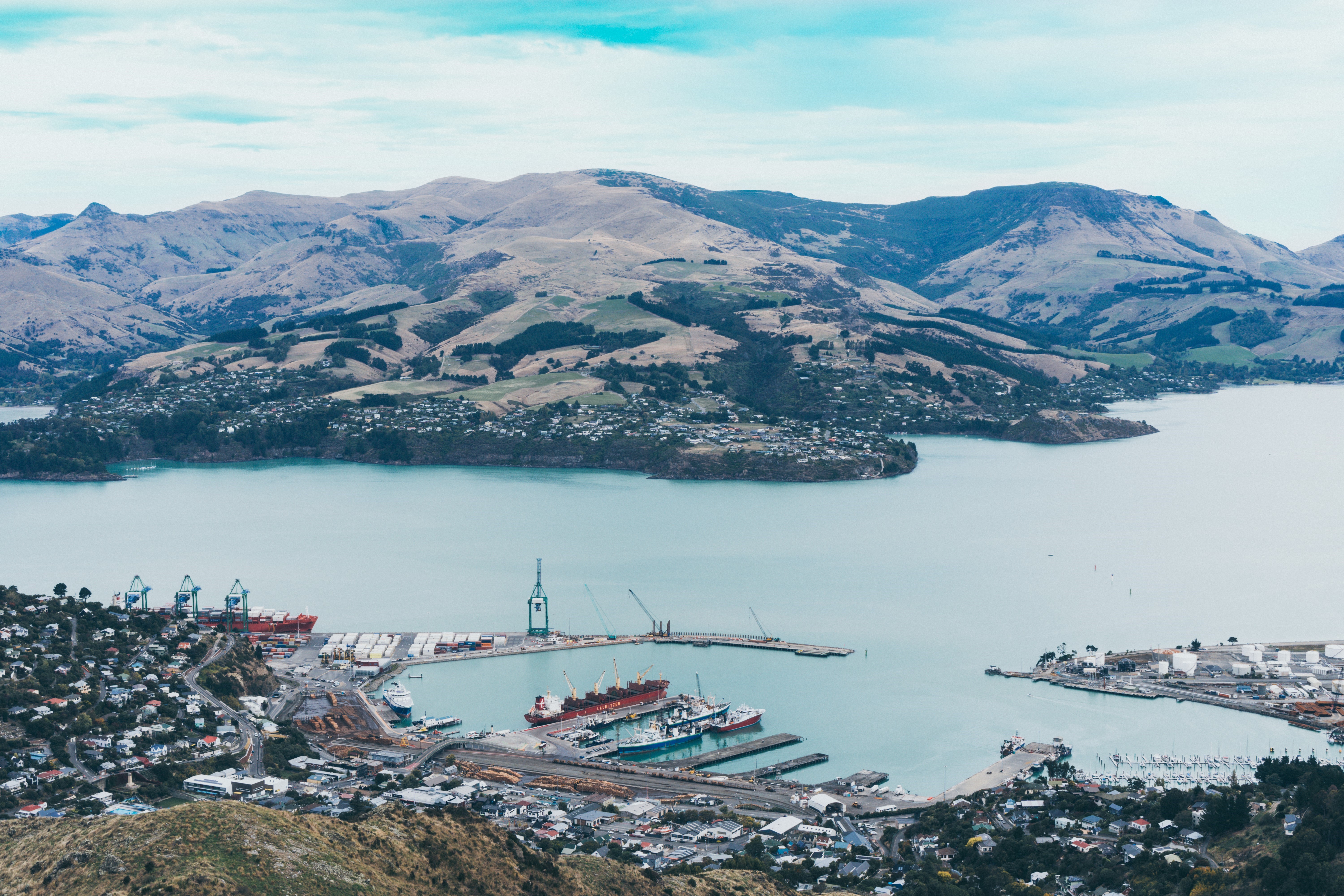 Port city nestled in a bay with mountains HD Wallpaper