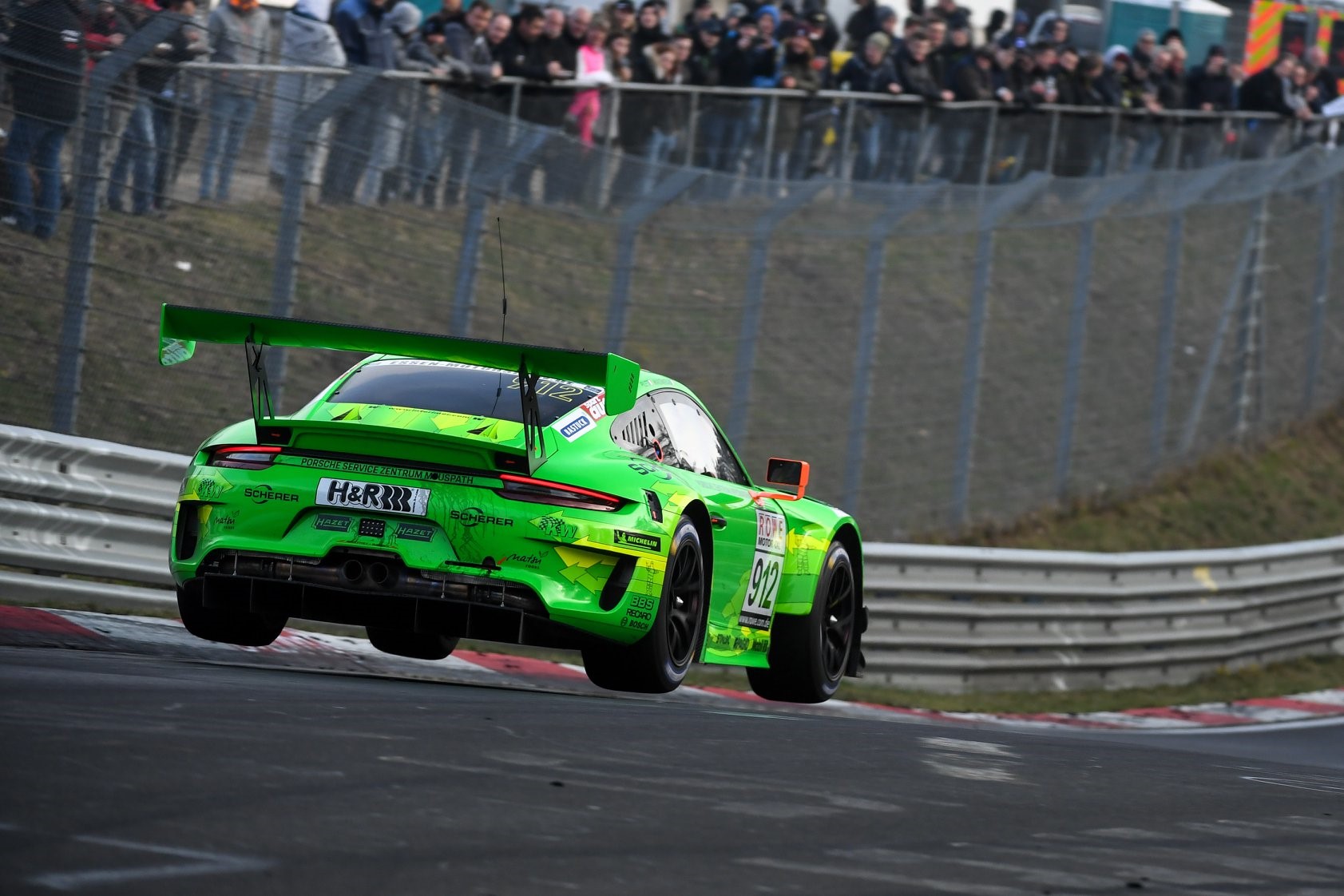 Green Porsche 911 GT3 R airborne on race track HD Wallpaper