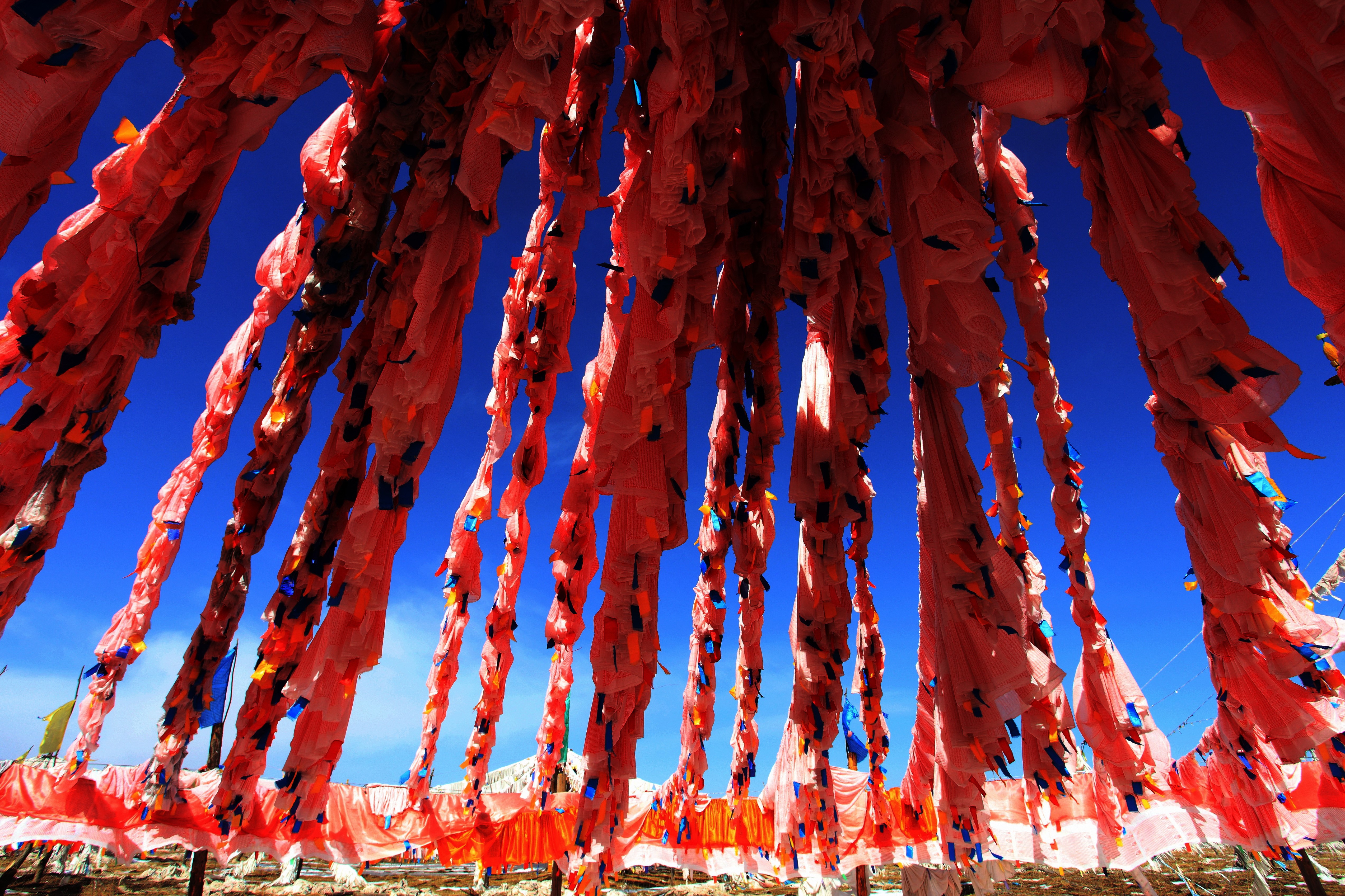 Red prayer flags in Tibet under a clear blue sky HD Wallpaper