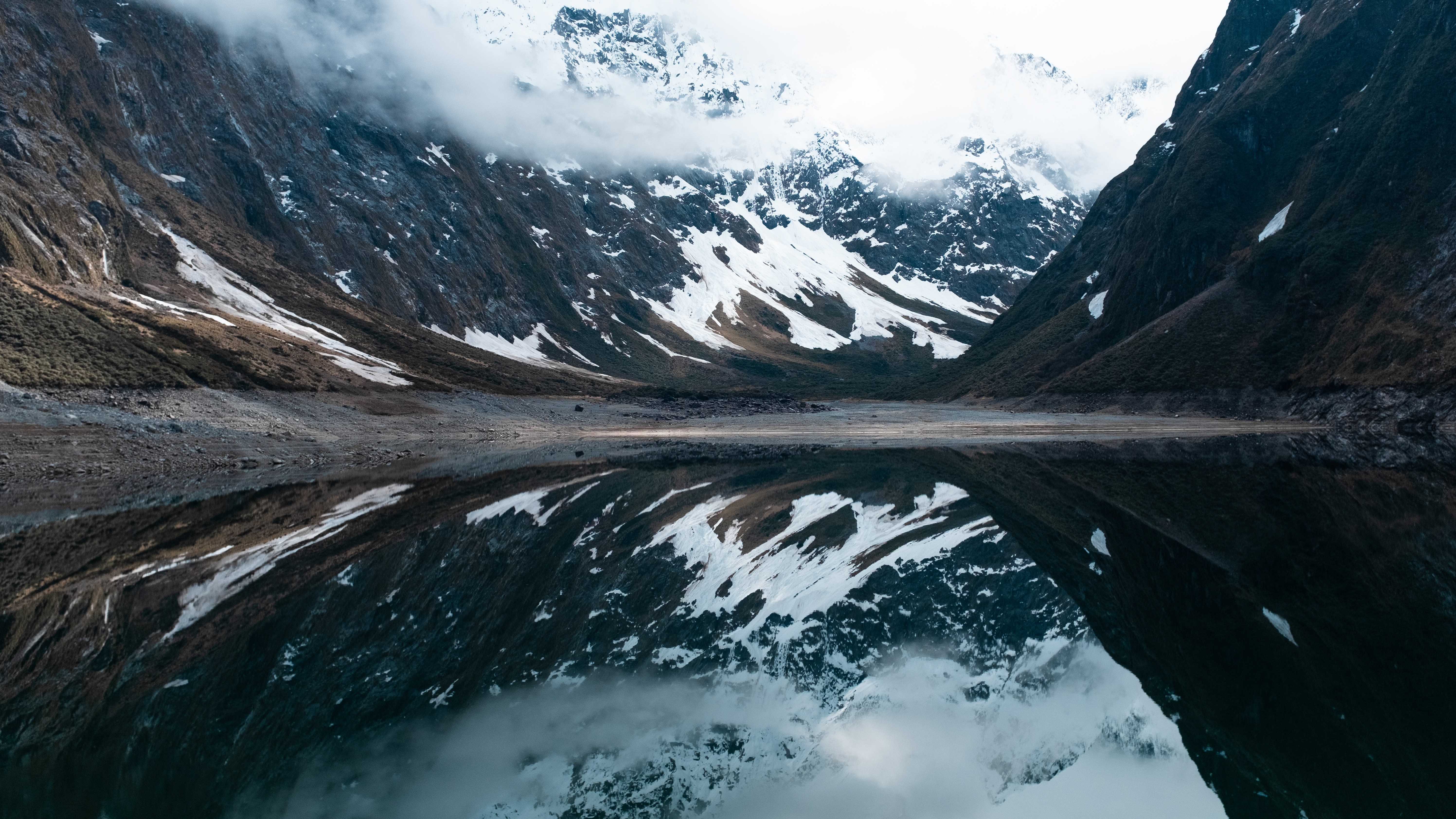 Snow-capped mountains reflected in a calm lake in Fiordland National Park, New Zealand HD Wallpaper