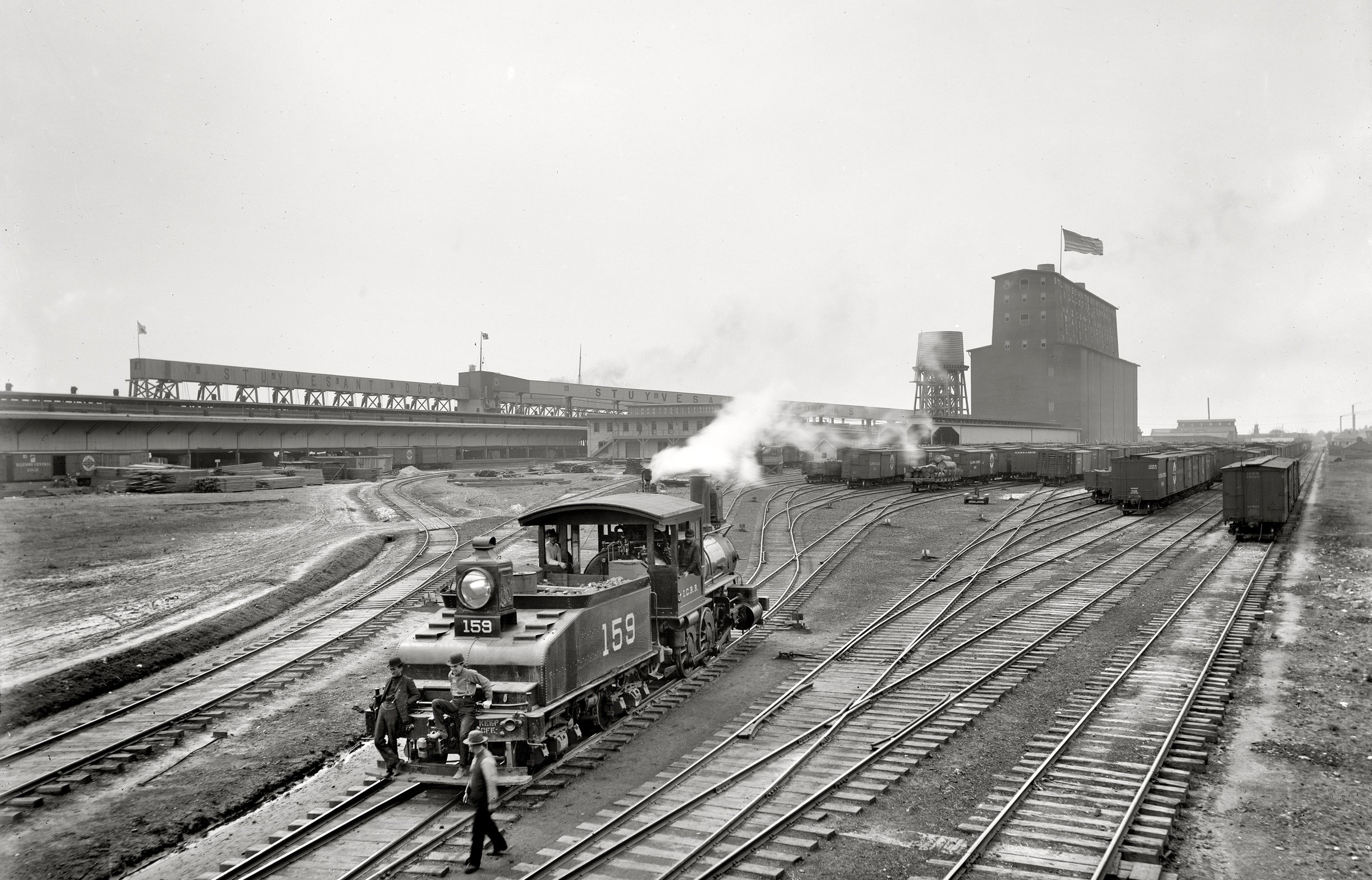 Train yard with locomotive and grain elevator HD Wallpaper