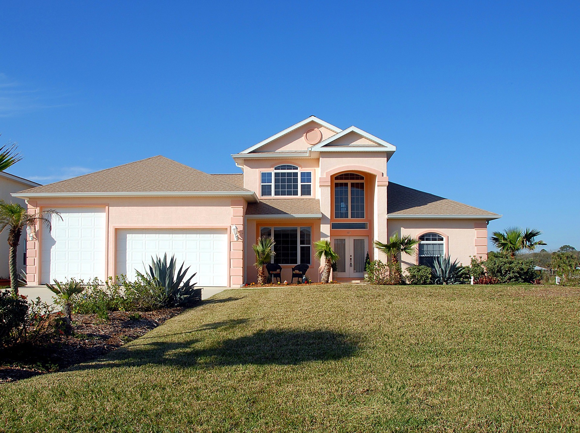 Peach stucco house with garages and palm trees HD Wallpaper