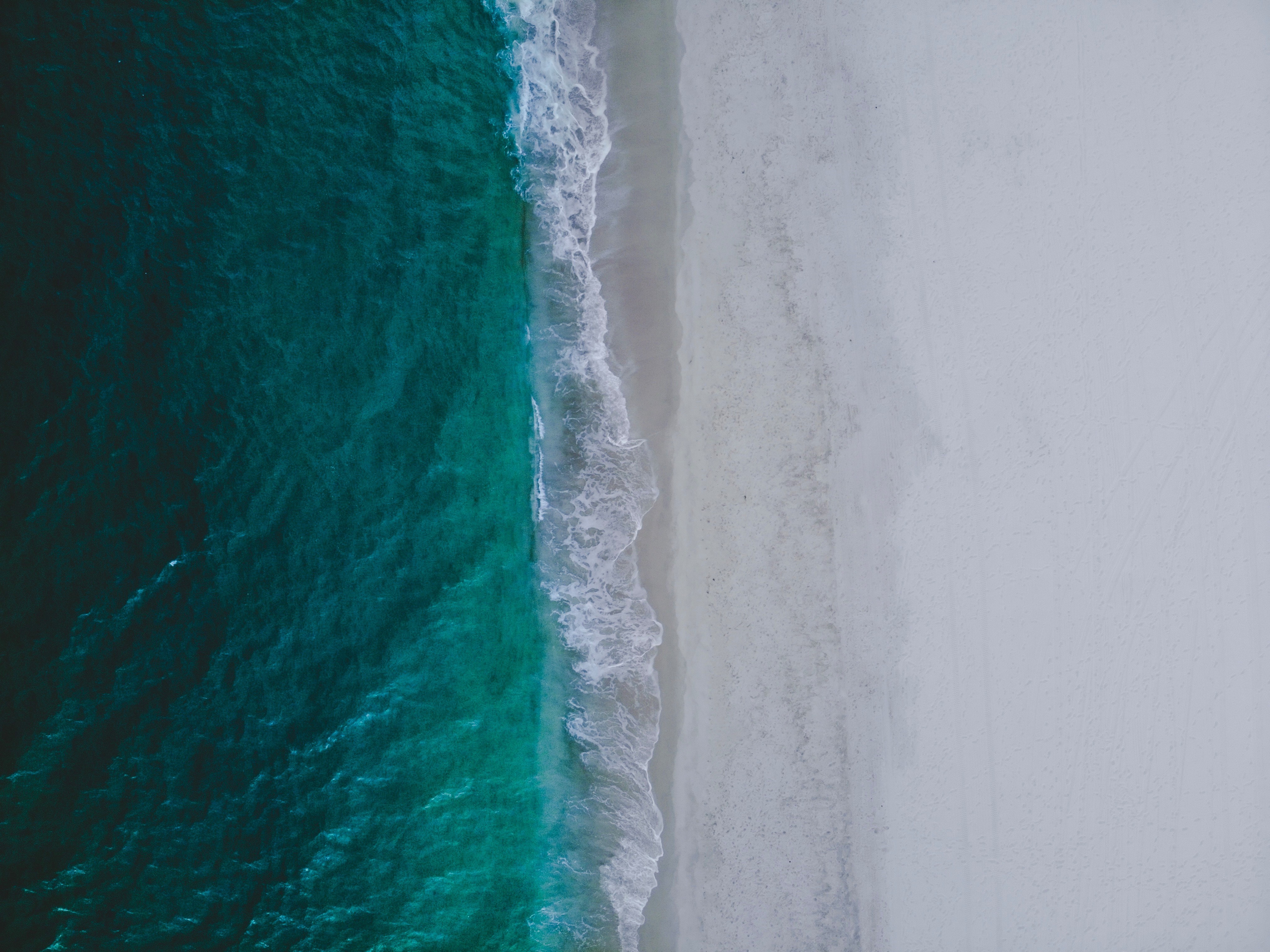 4K Aerial View of Ocean Waves on a Sandy Beach HD Wallpaper