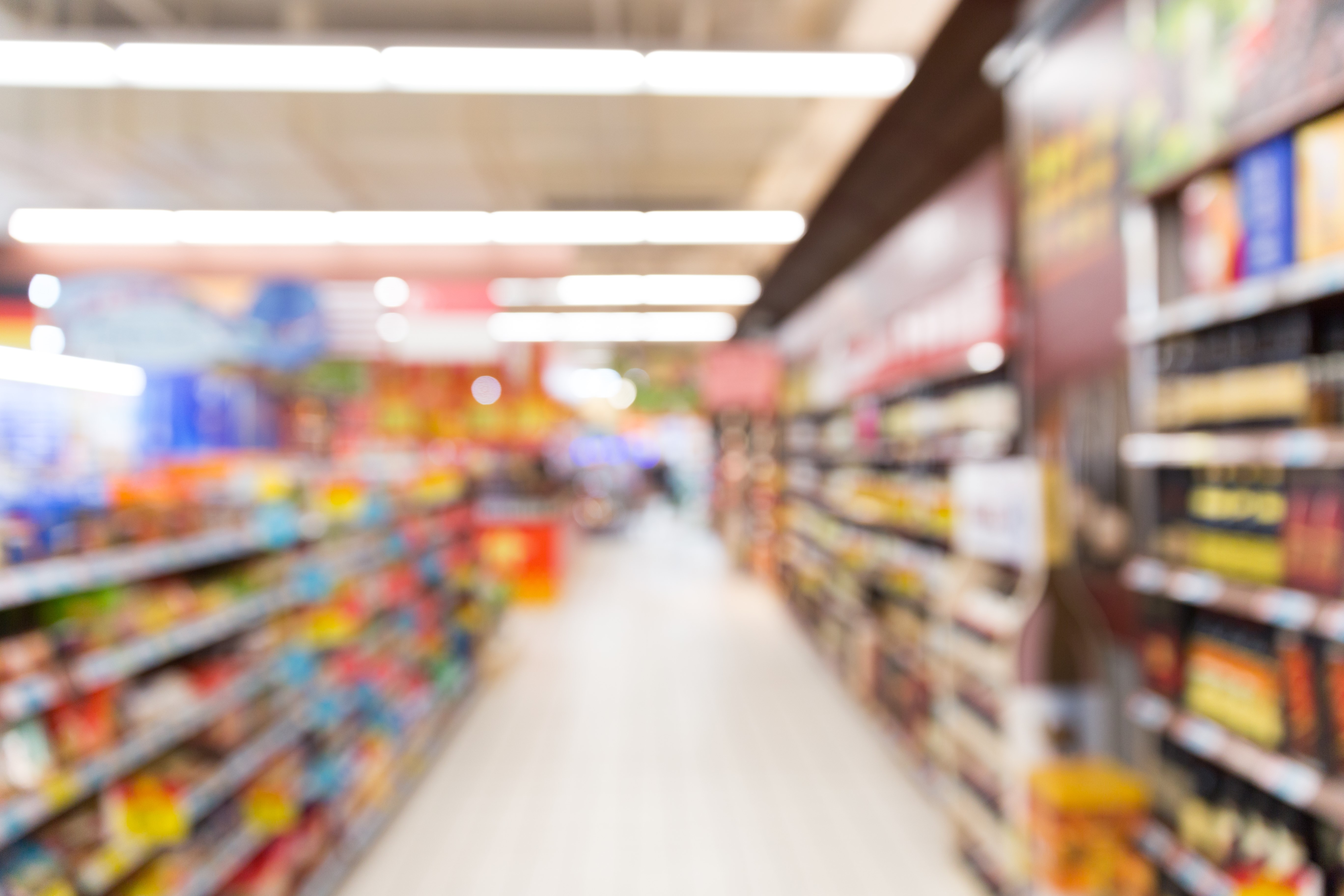 Blurred supermarket aisle with shelves of products HD Wallpaper