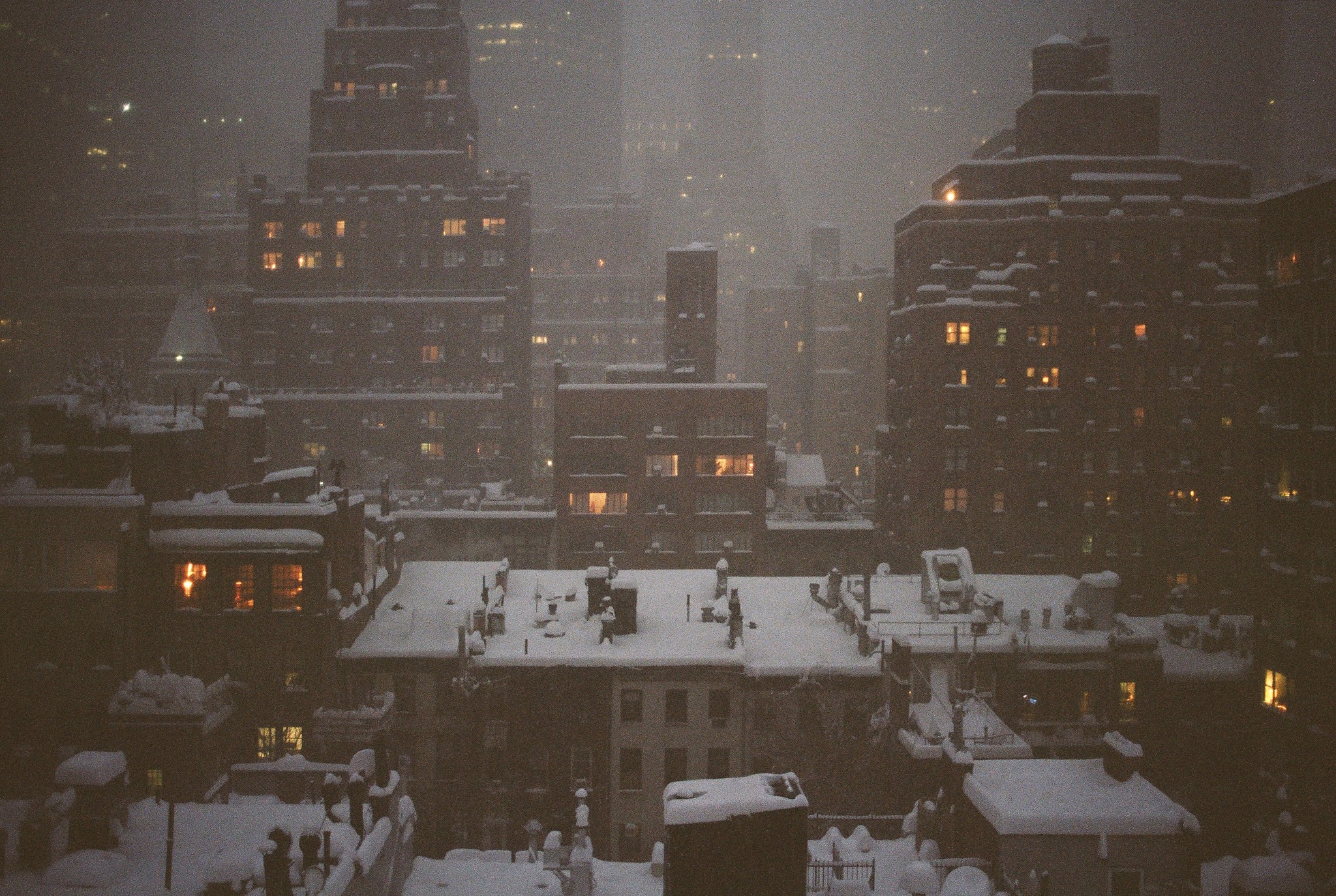 Snowy city skyline at night with illuminated windows HD Wallpaper