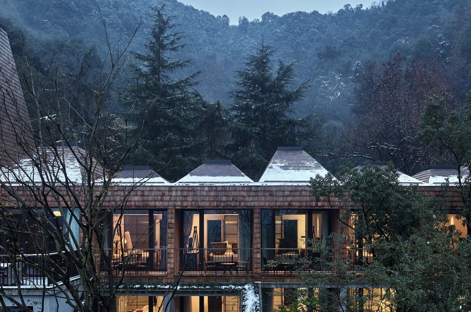 Modern architecture building with snow-covered roofs in a forest HD Wallpaper