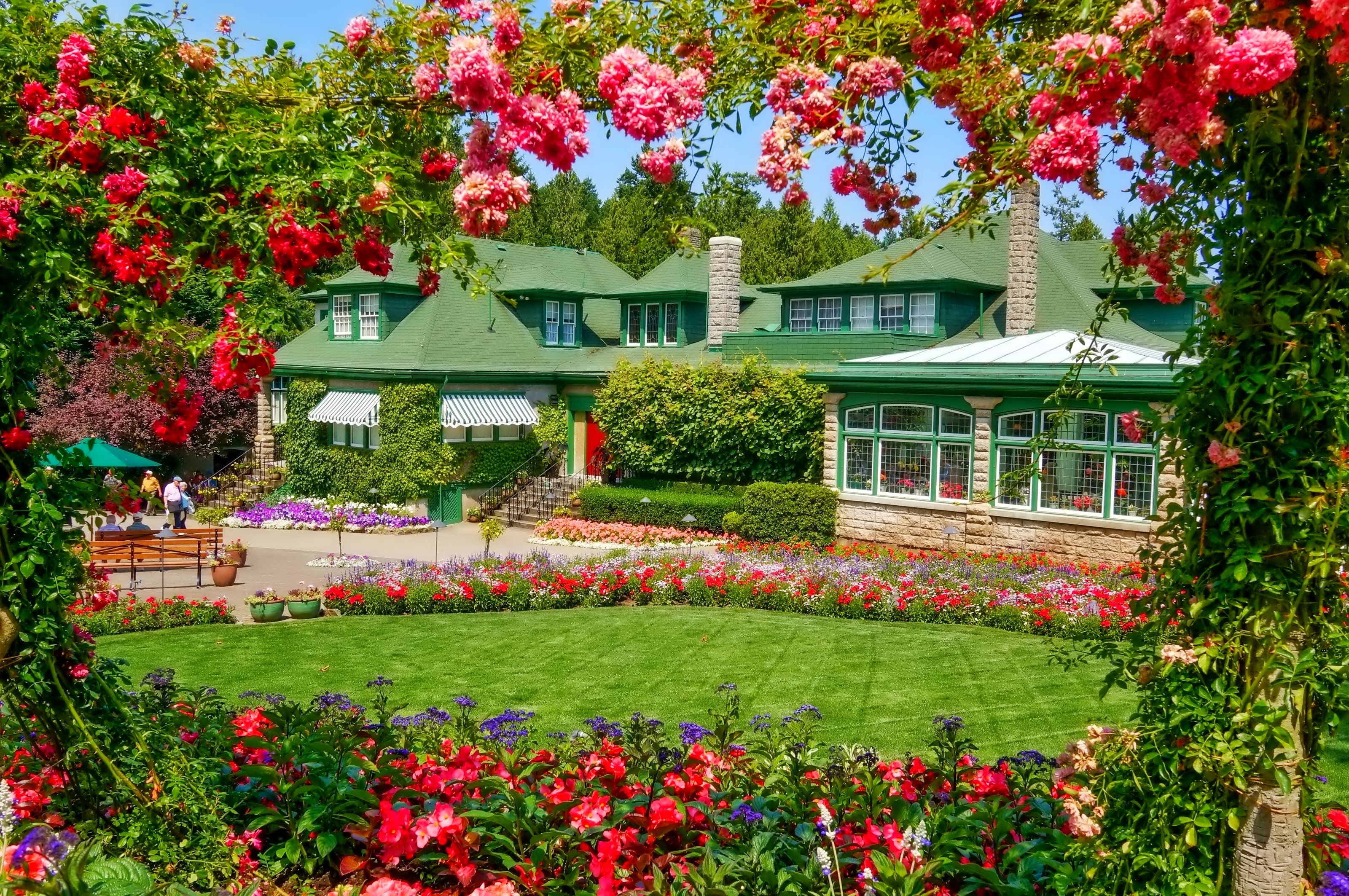 A grand mansion with a vibrant floral garden HD Wallpaper