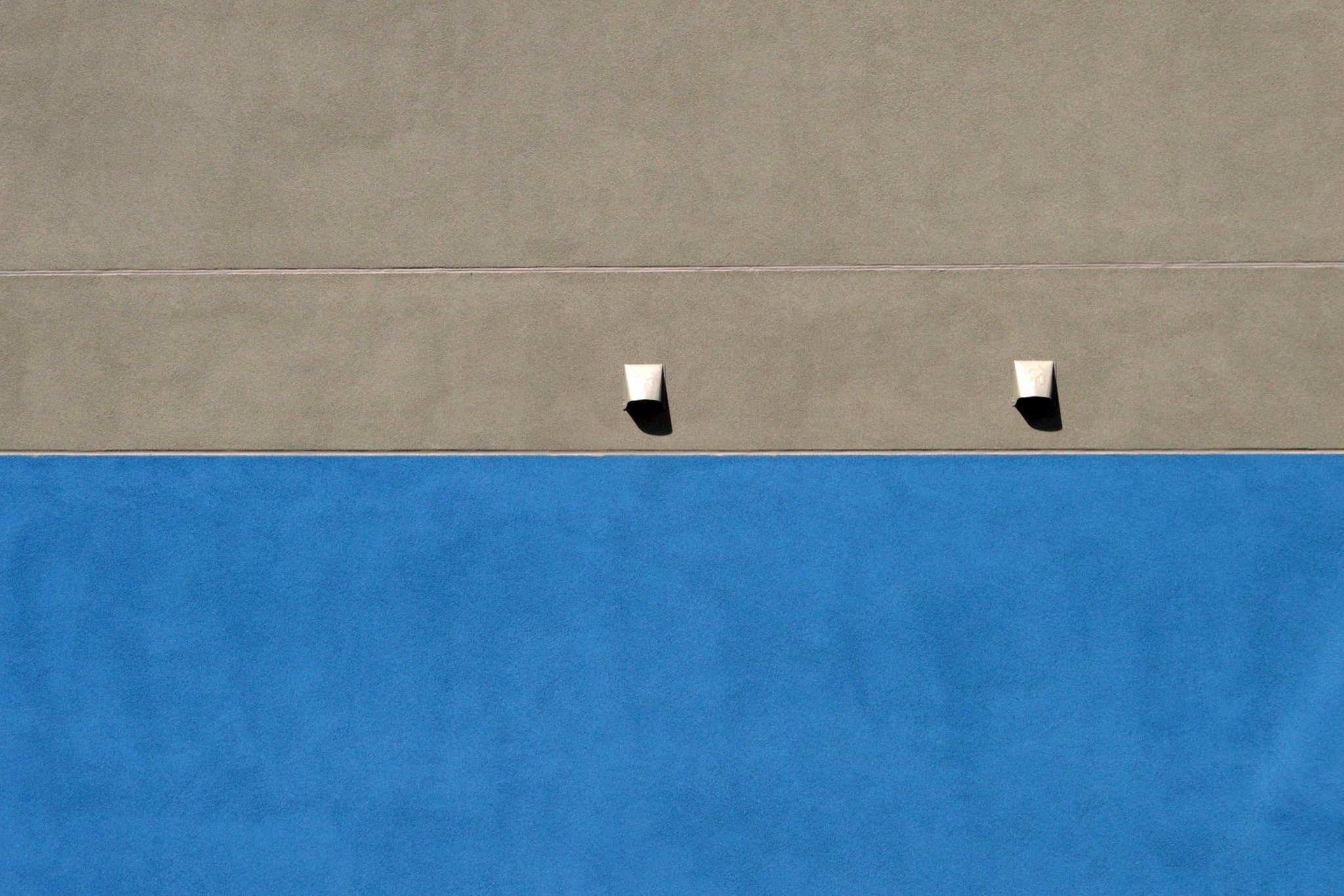 Two lights on a building wall with blue and tan sections HD Wallpaper