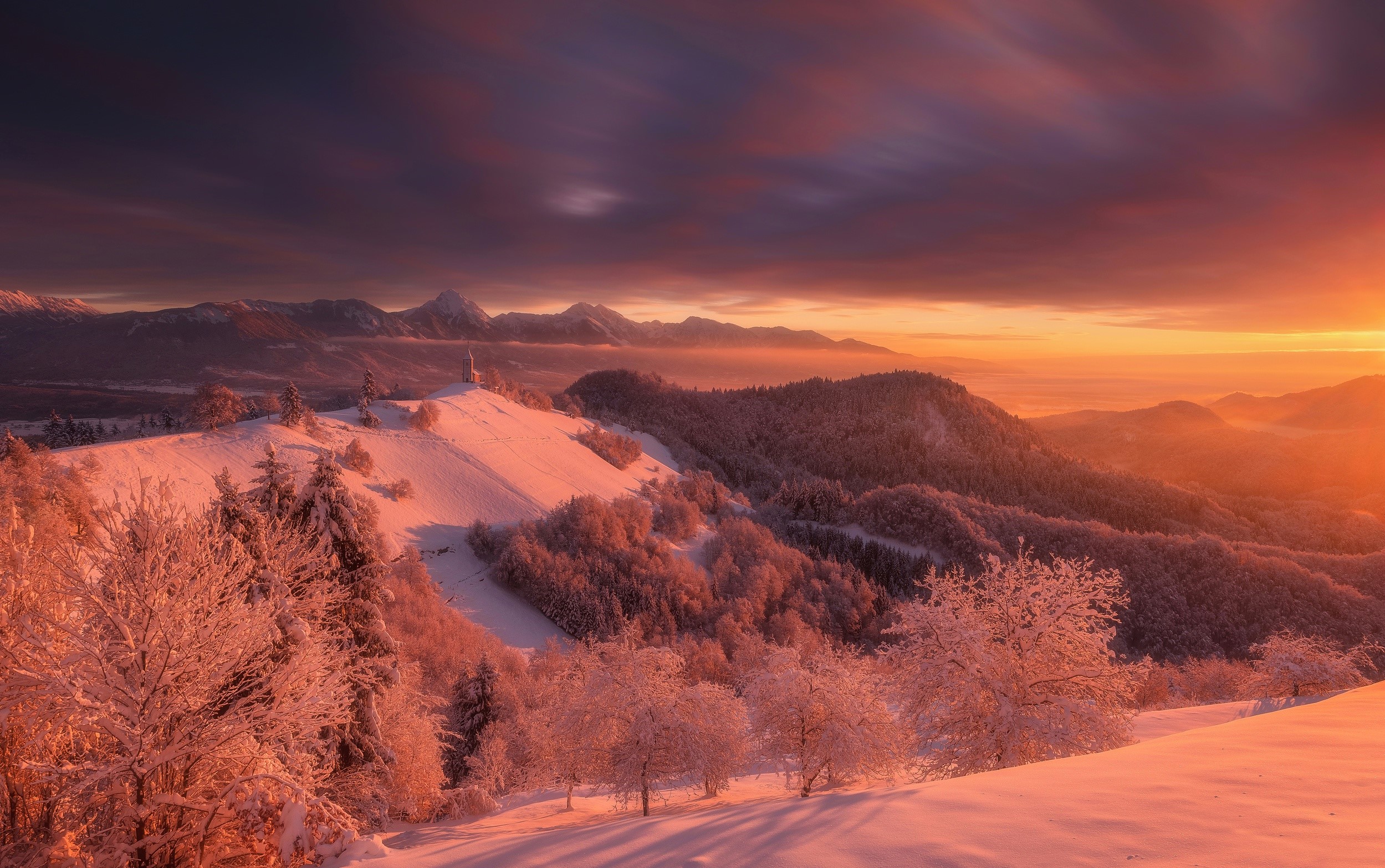 Snowy mountain landscape at sunset with a church on a hill HD Wallpaper