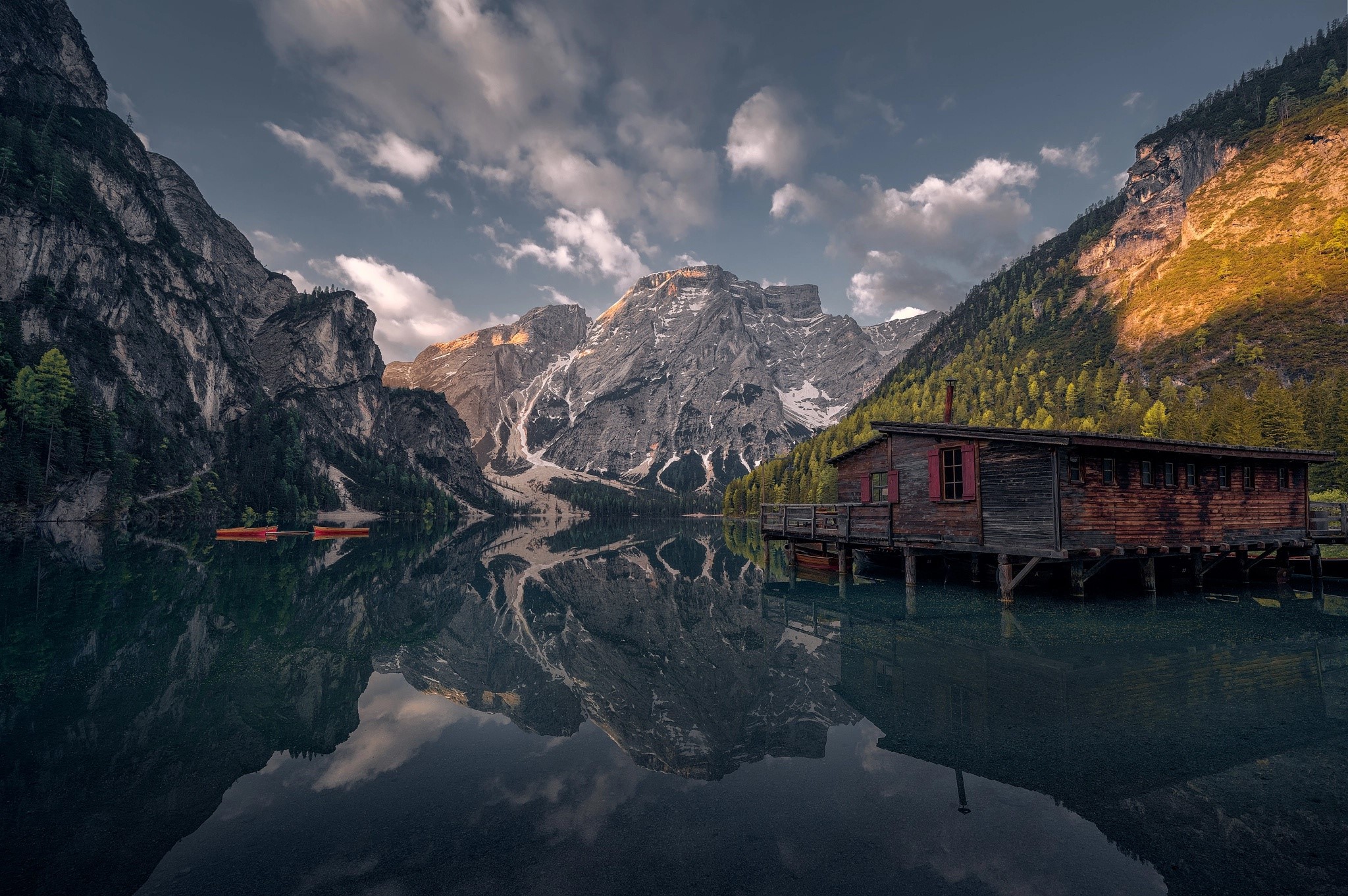 Wooden boathouse on a calm lake with mountains reflecting HD Wallpaper
