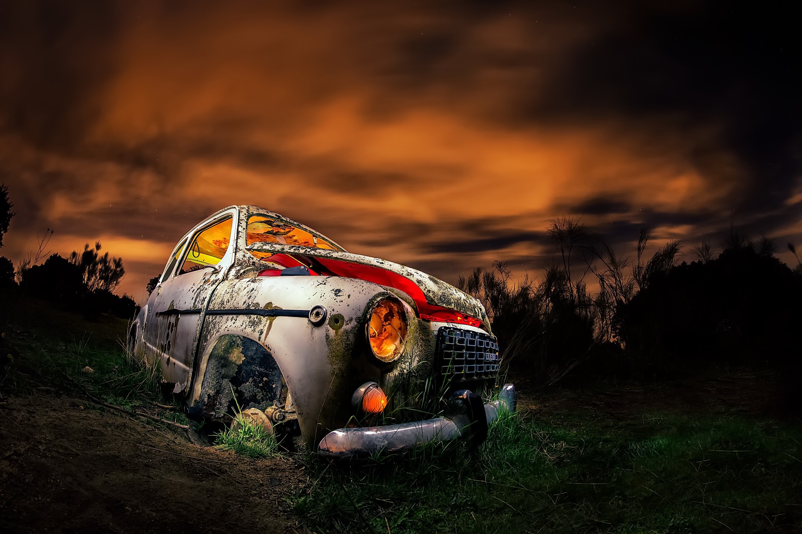 Abandoned car in a dark, cloudy landscape HD Wallpaper