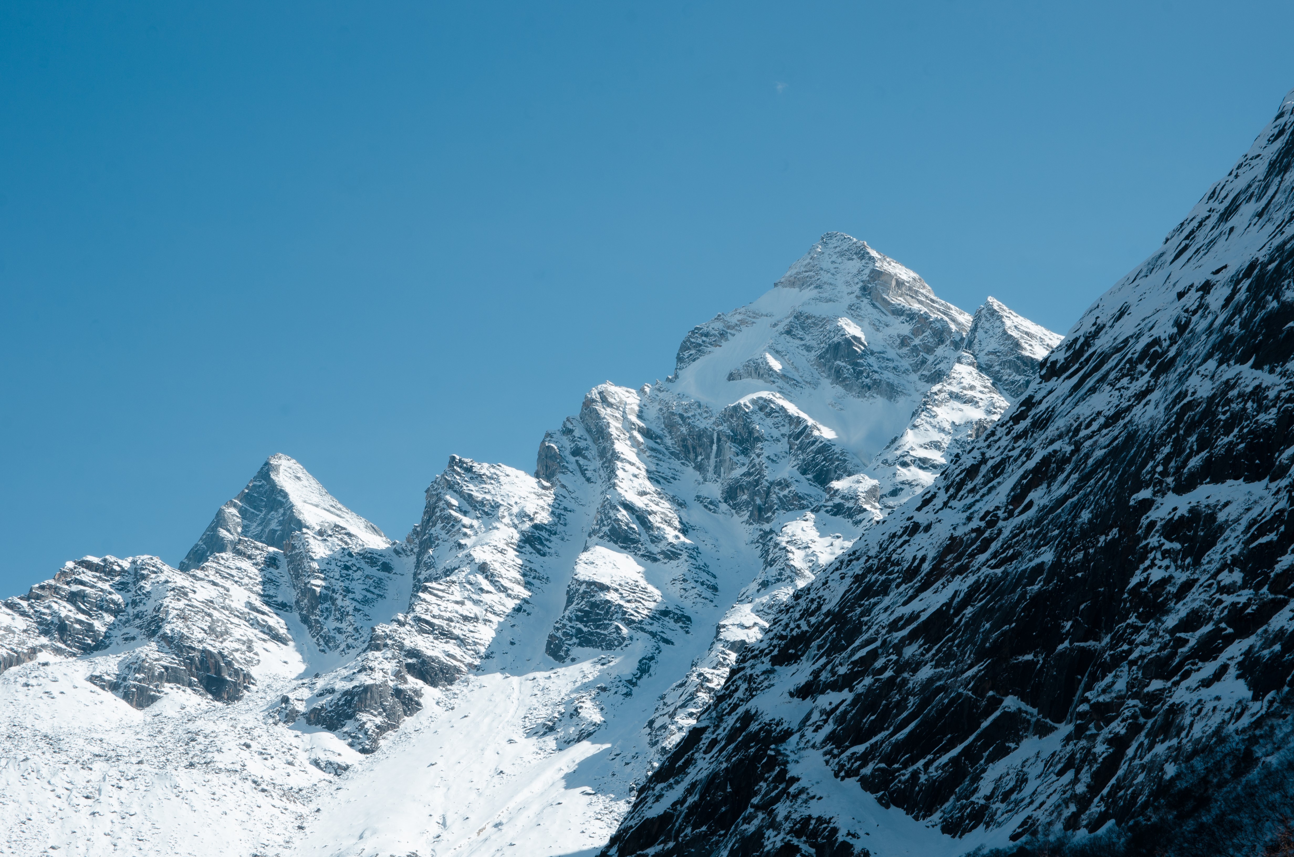 Snow-covered mountains under a clear blue sky in Sichuan, China HD Wallpaper