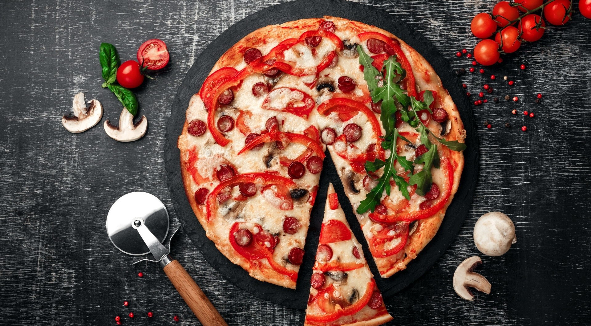 Pizza with tomatoes, mushrooms, and peppers on a dark surface HD Wallpaper