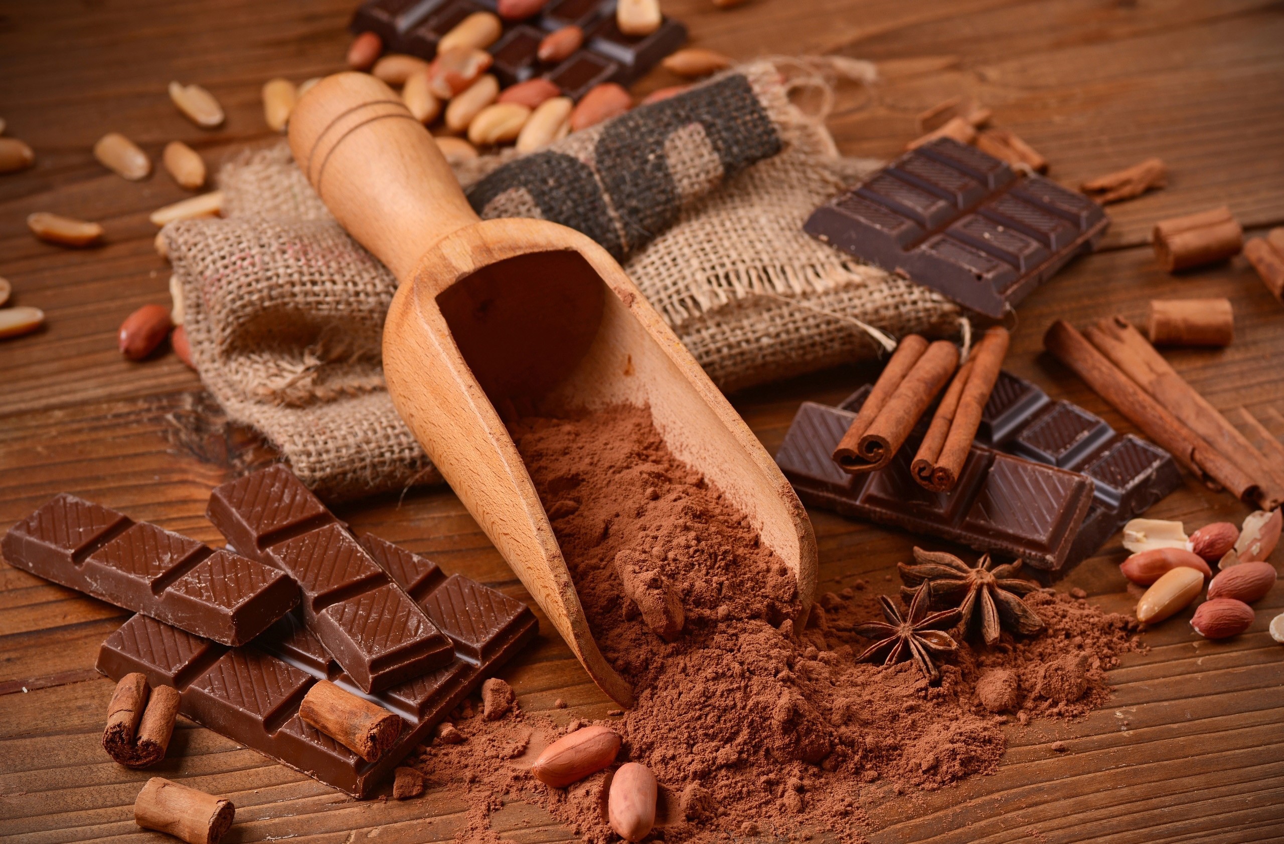 Chocolate, cocoa powder, cinnamon, and peanuts on a wooden table HD Wallpaper