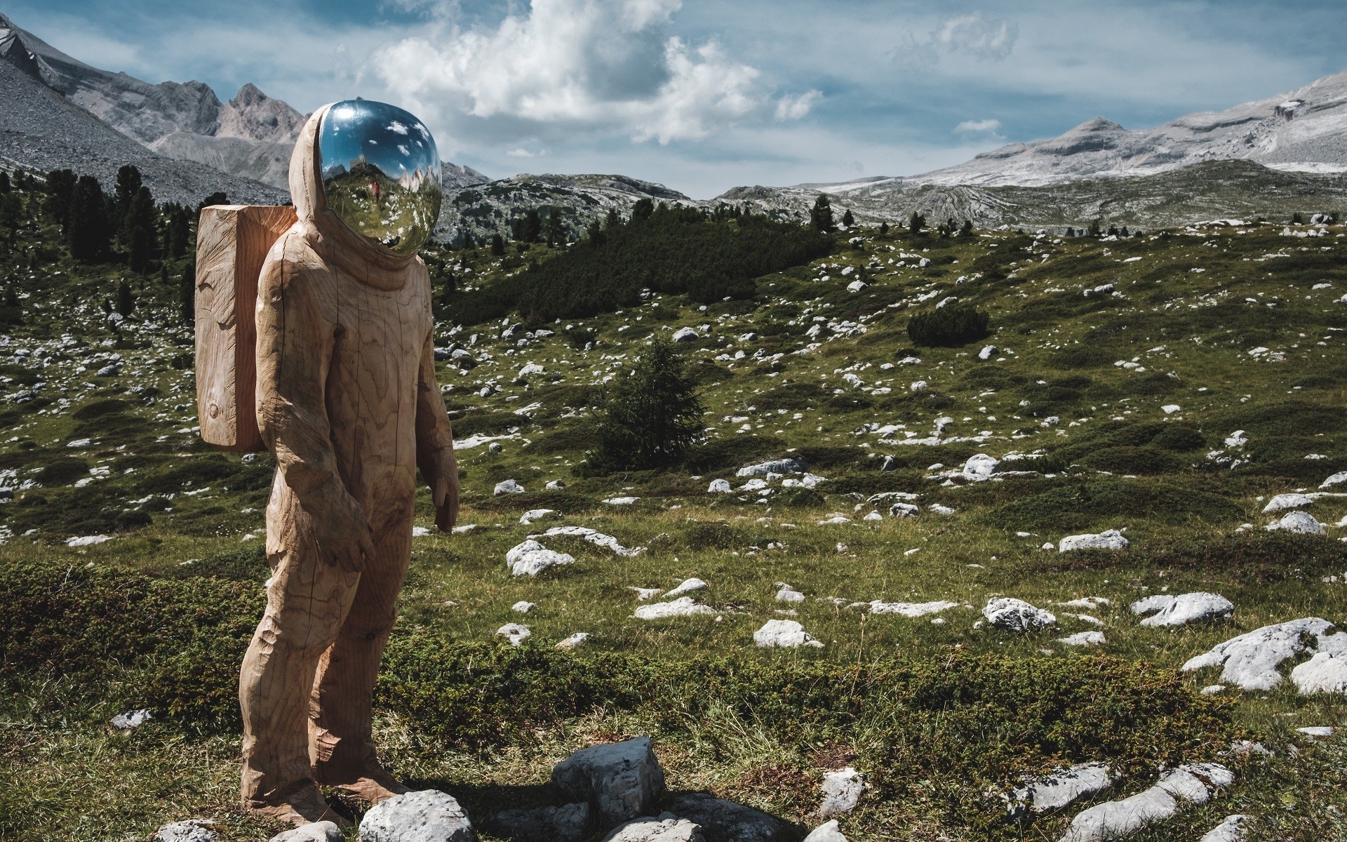 Wooden astronaut statue in a mountain landscape HD Wallpaper