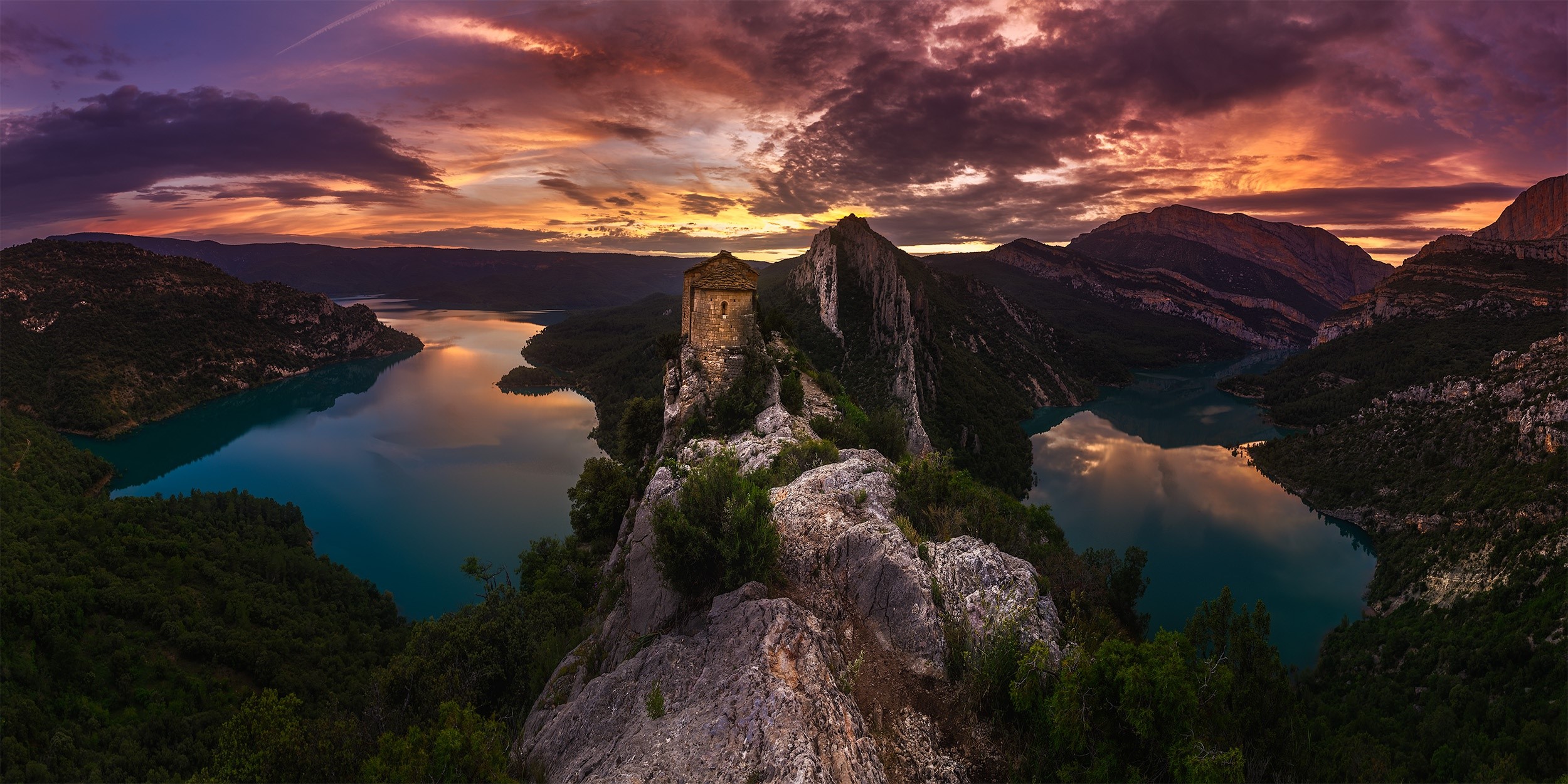 Castle on a rocky outcrop overlooking a lake at sunset HD Wallpaper