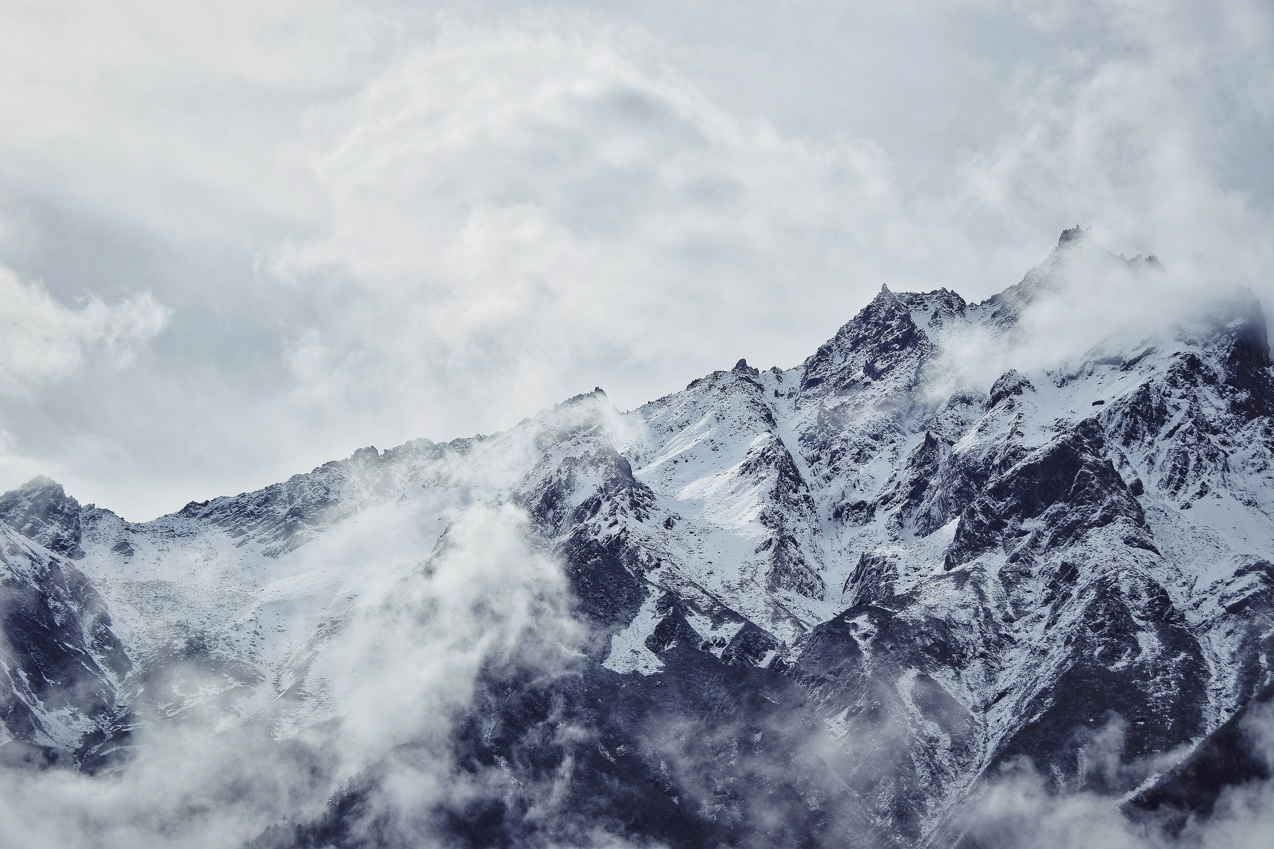 Snowy mountain peaks shrouded in clouds HD Wallpaper