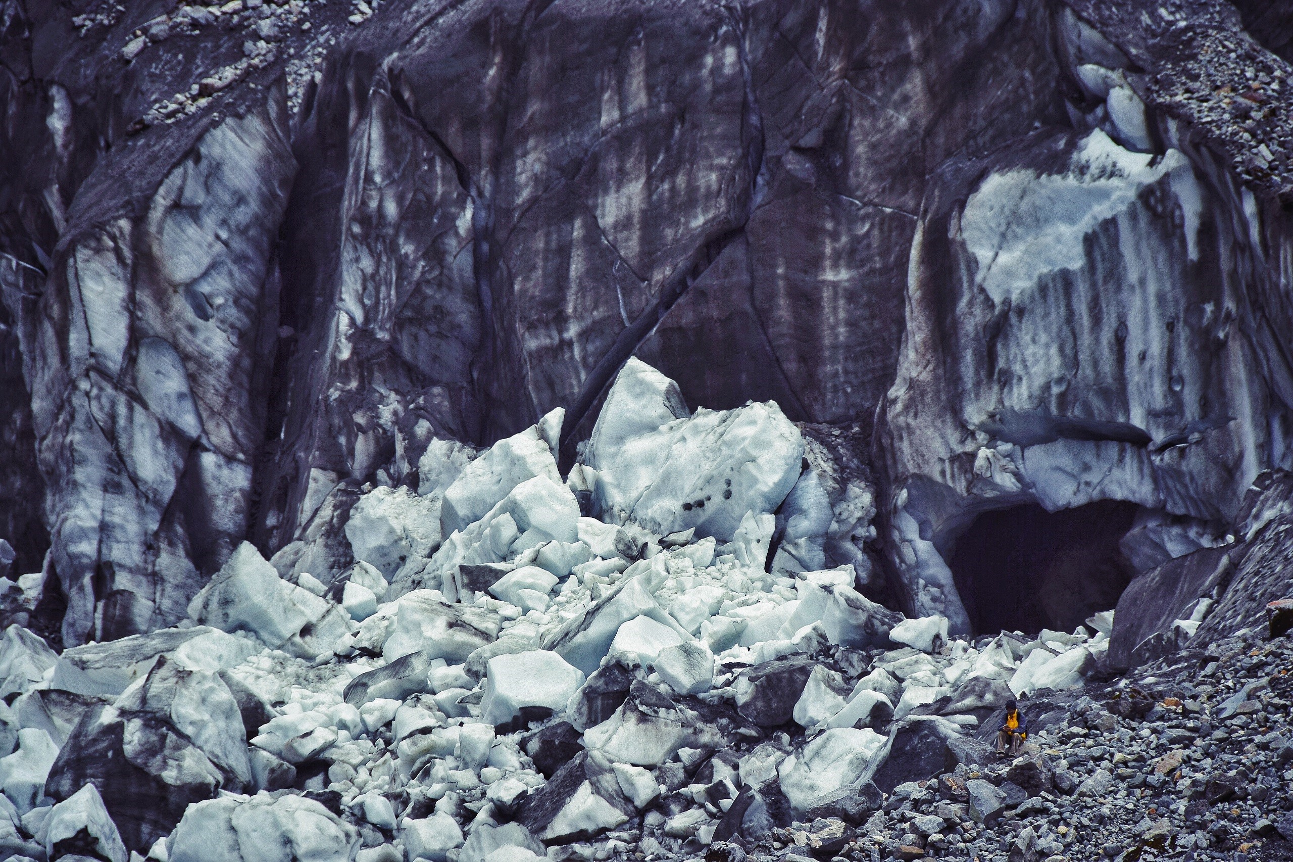 Glacier cave with ice chunks and a person HD Wallpaper