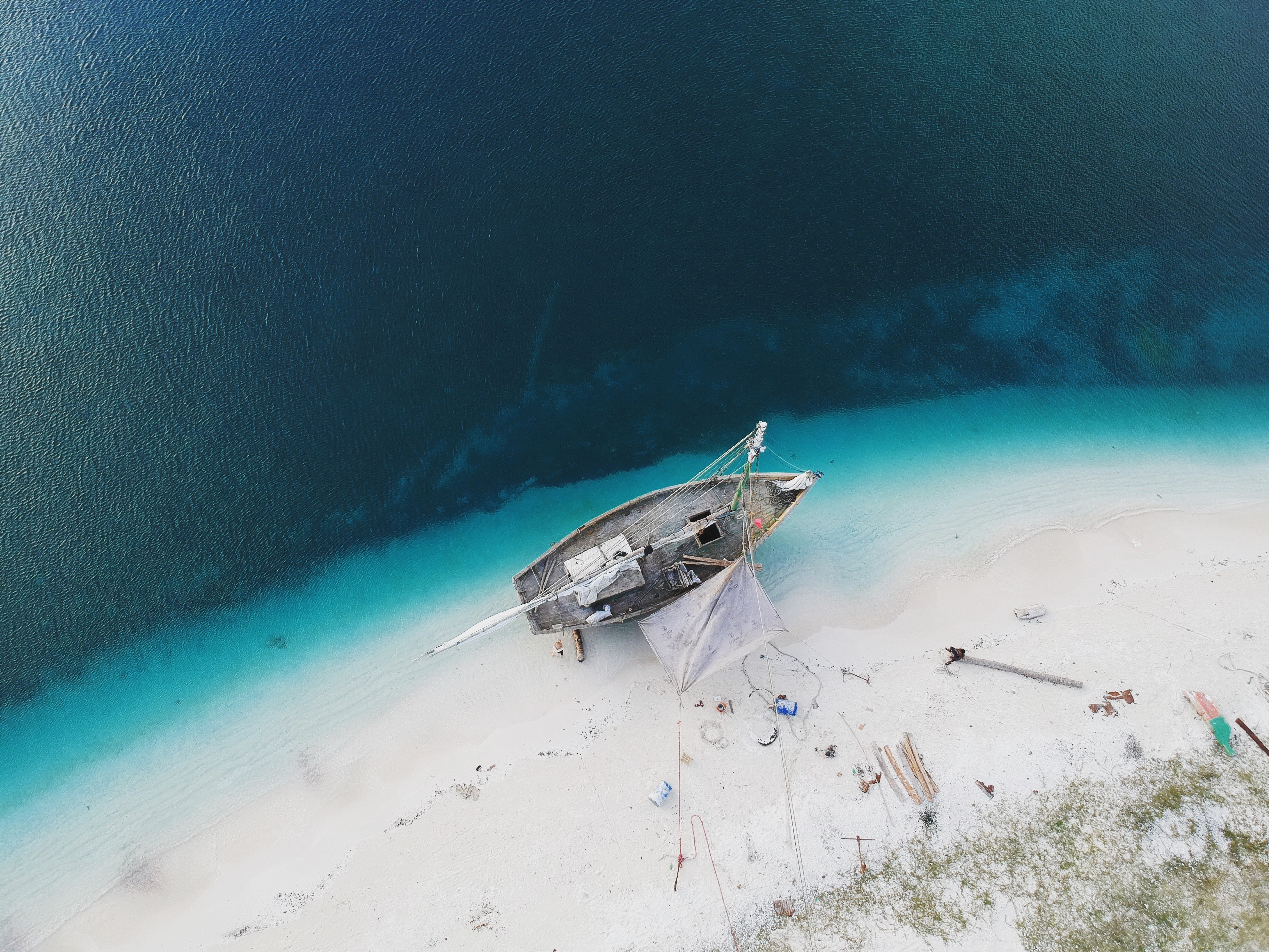 Boat stranded on a tropical beach from a bird's eye view HD Wallpaper
