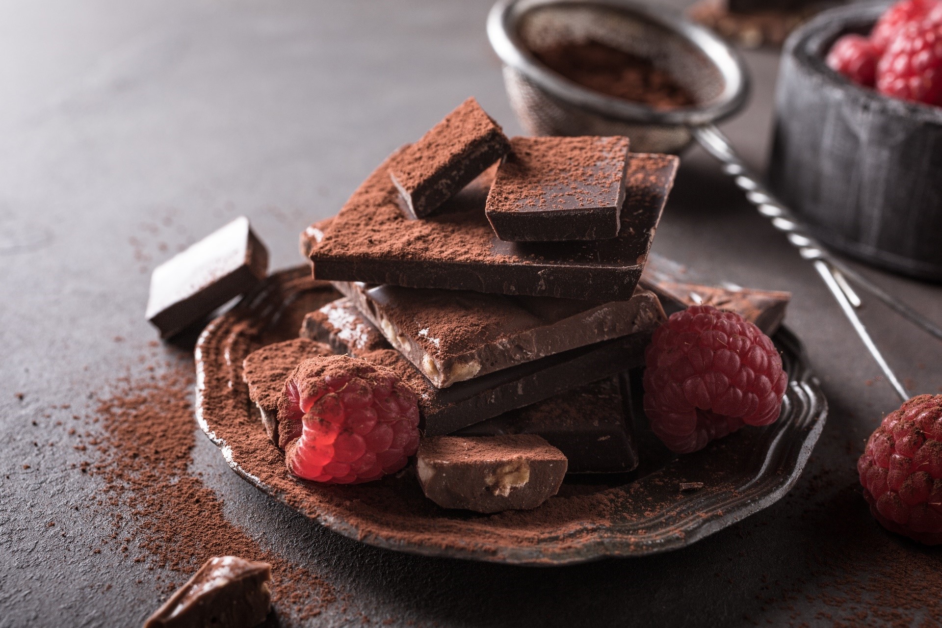 Chocolate pieces and raspberries on a dark surface HD Wallpaper